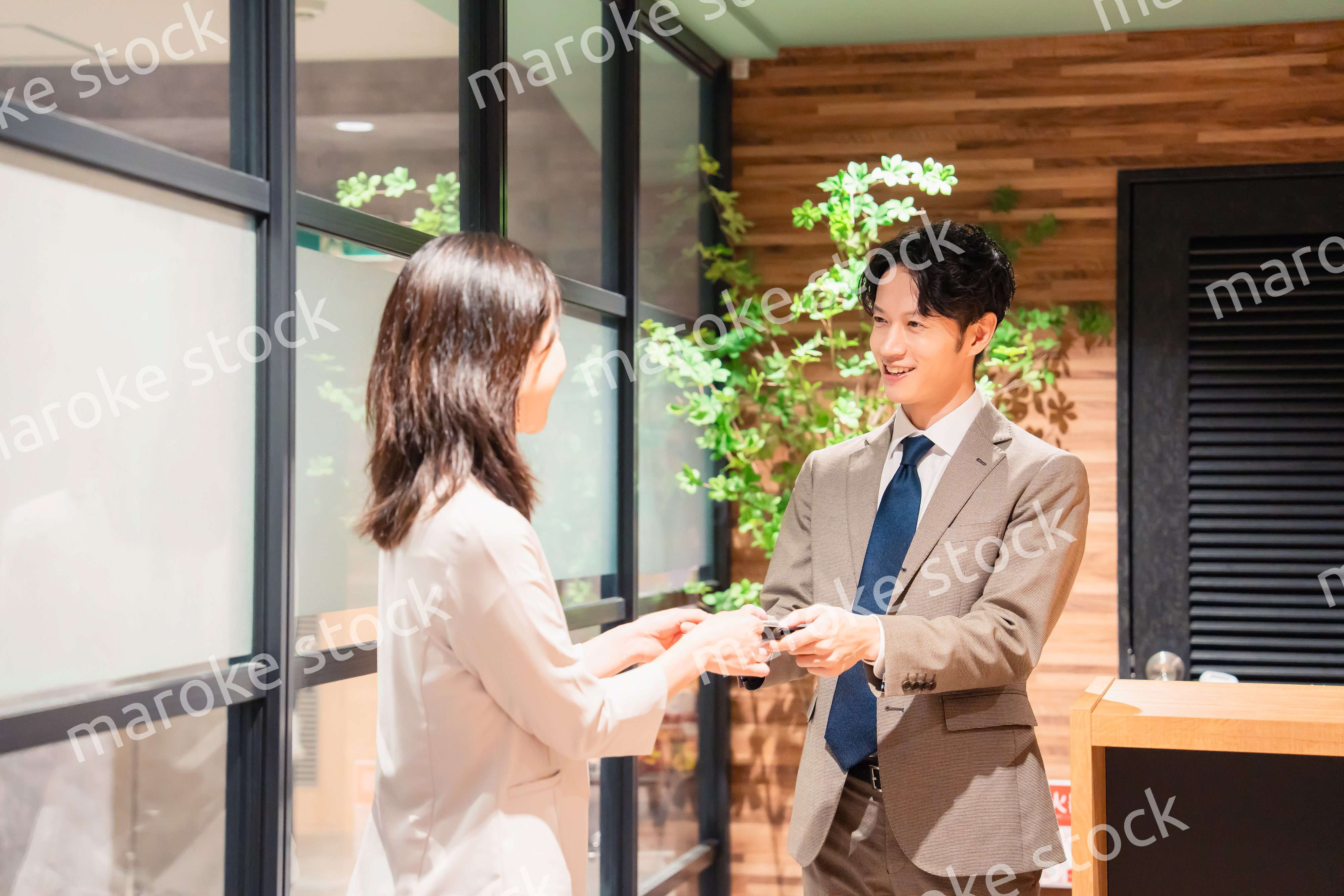 オフィスのエントランスで名刺交換をするビジネスパーソン