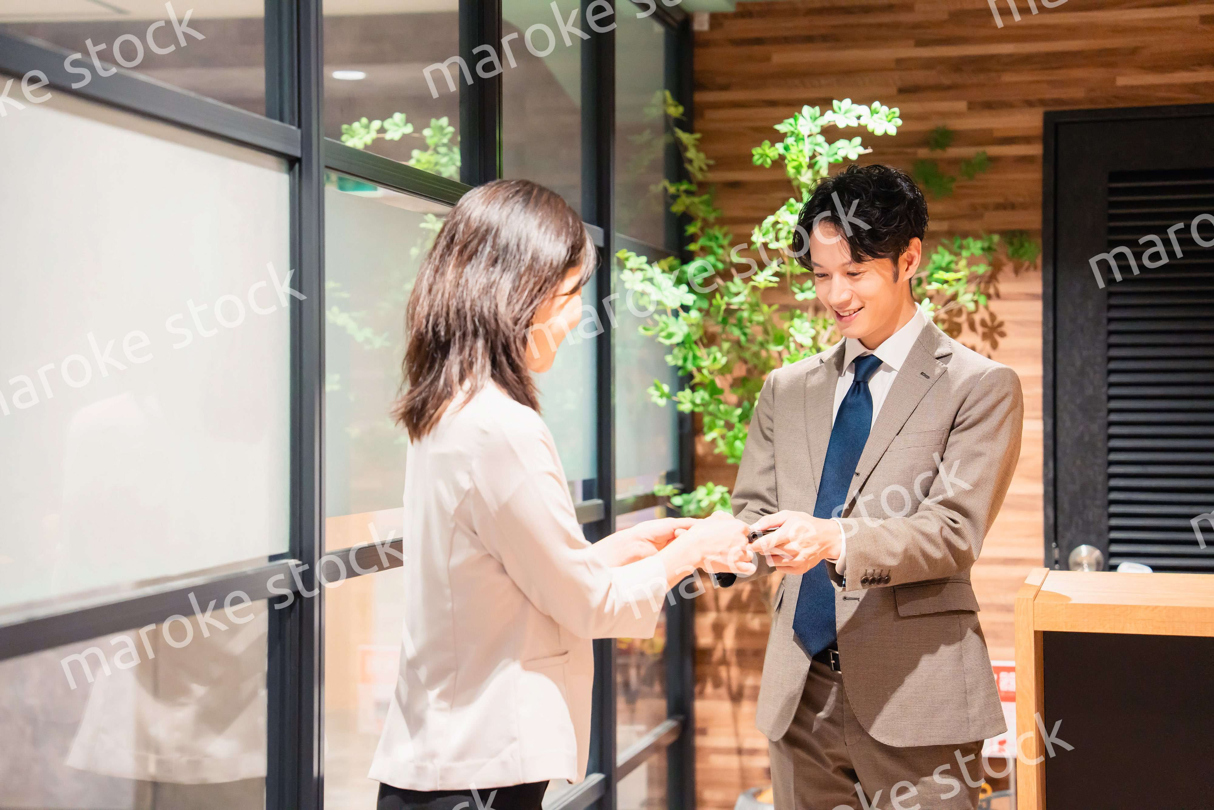 オフィスのエントランスで名刺交換をするビジネスパーソン