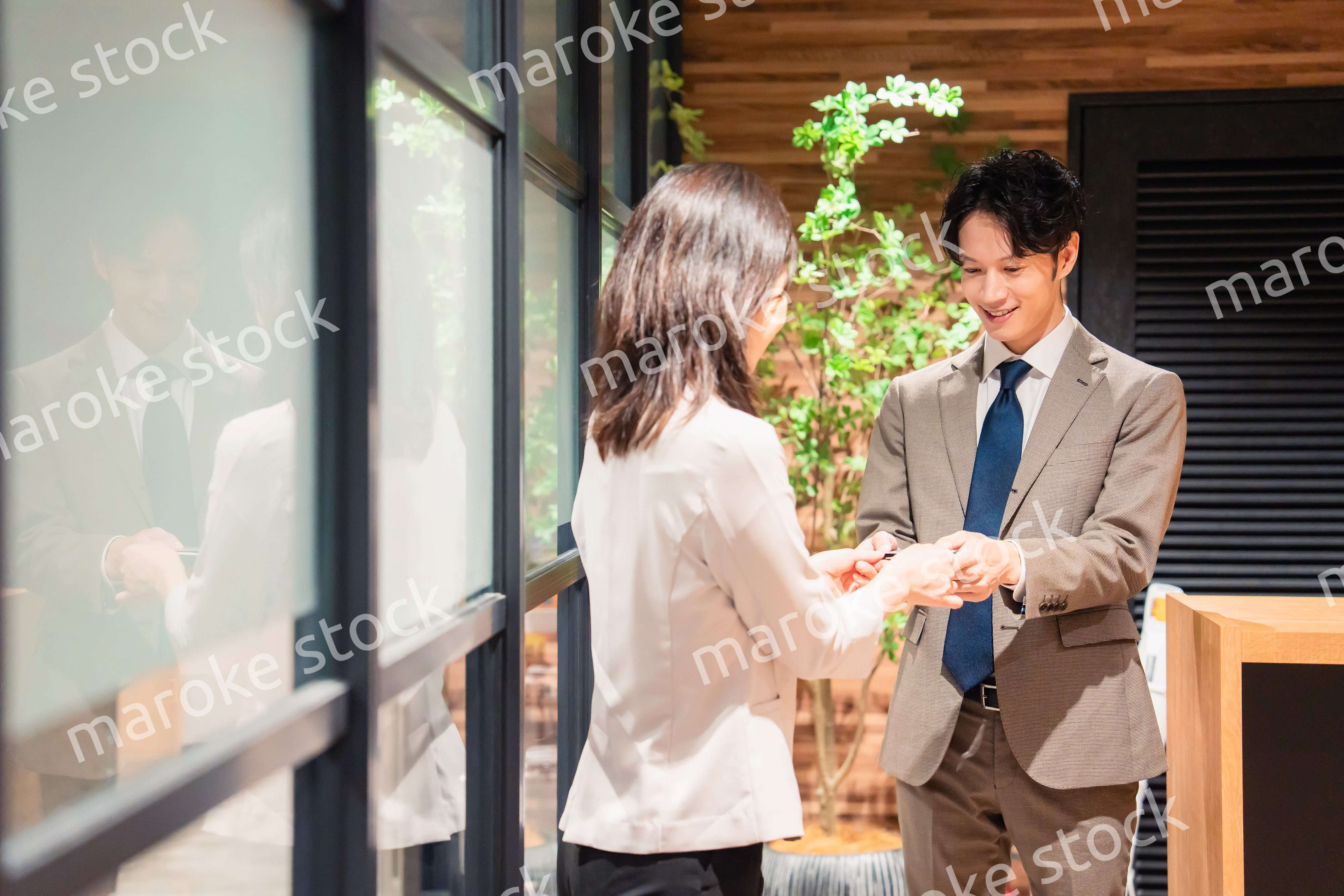 オフィスのエントランスで名刺交換をするビジネスパーソン