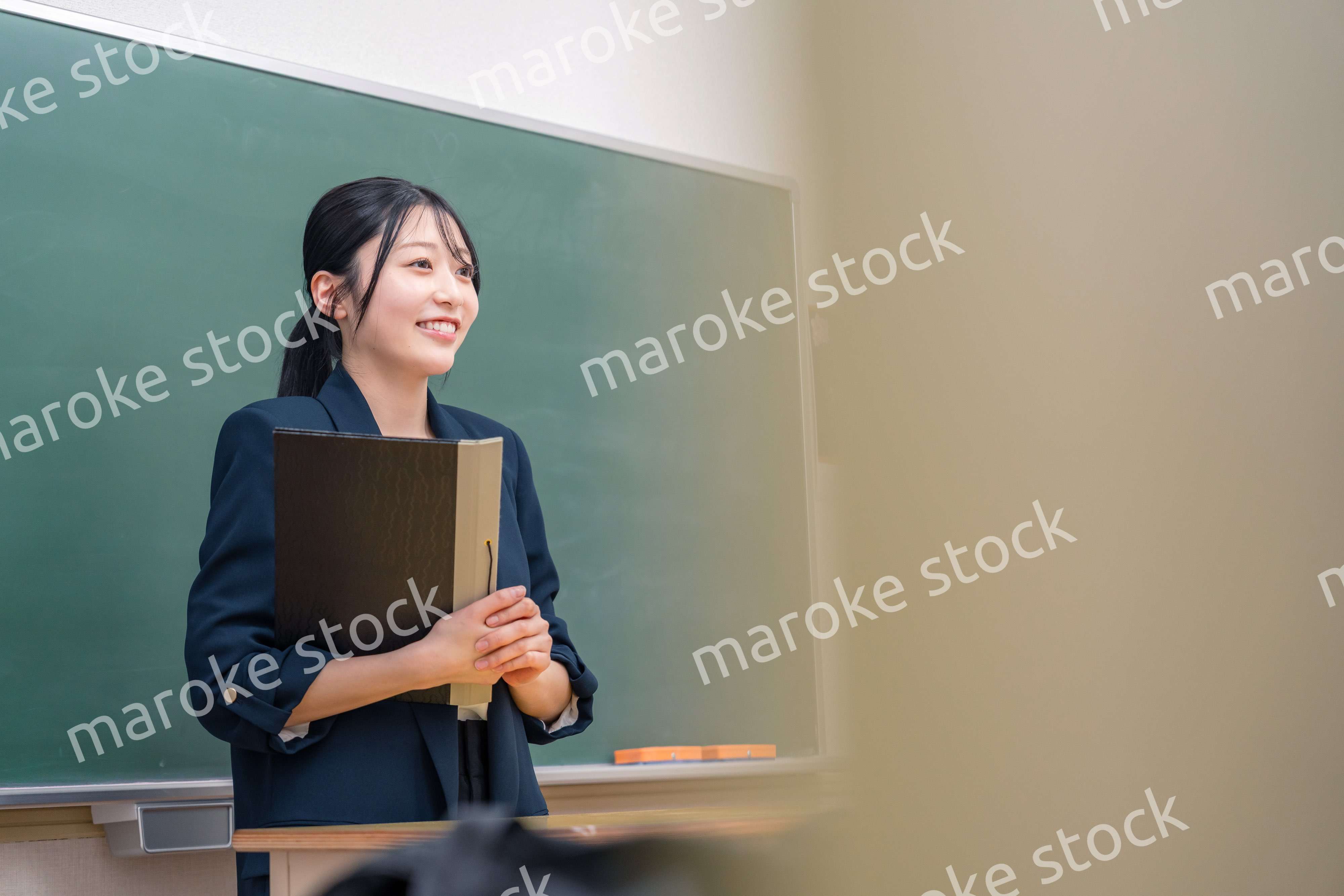 学校で教壇に立って授業をする若い女性教師