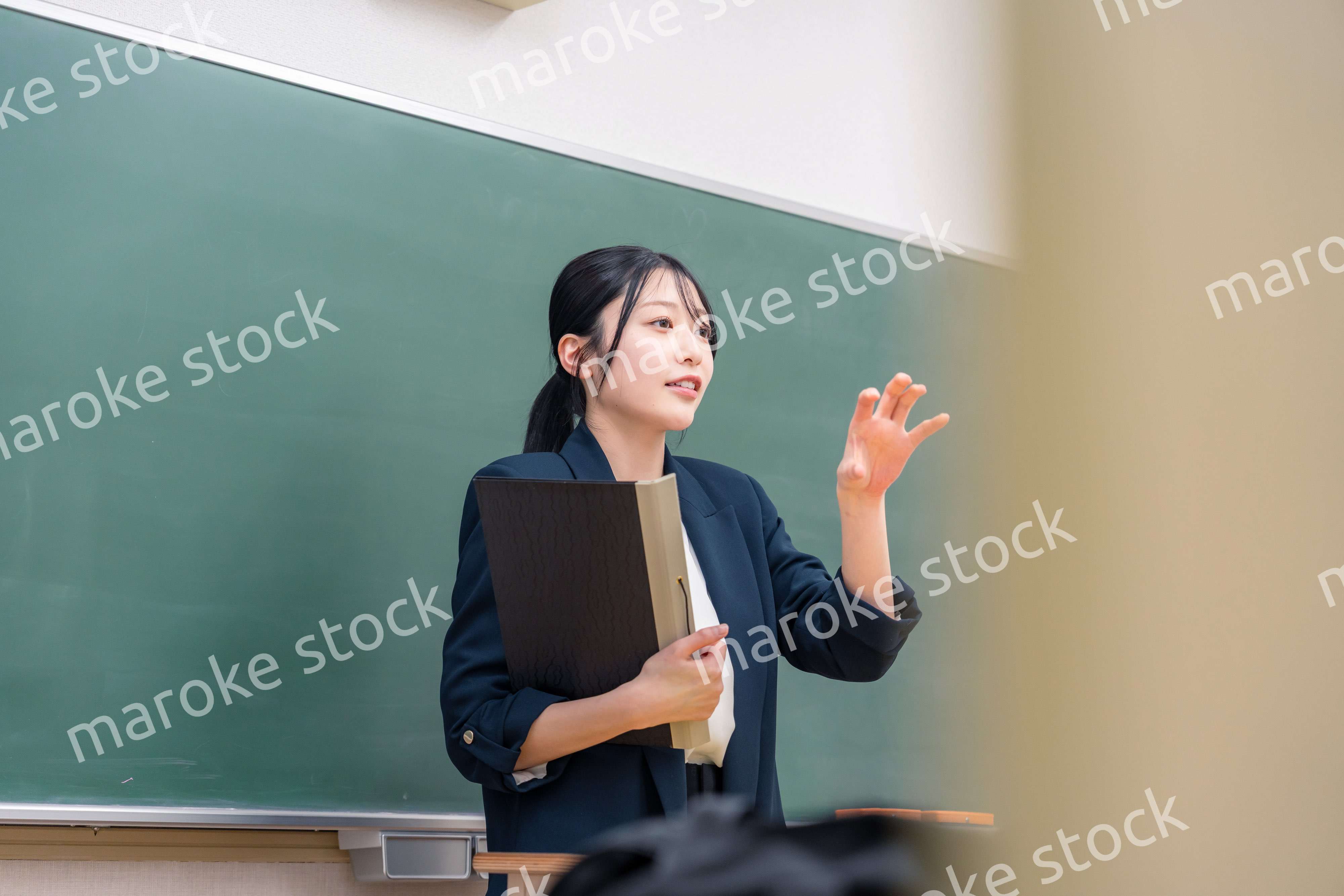 学校で教壇に立って授業をする若い女性教師
