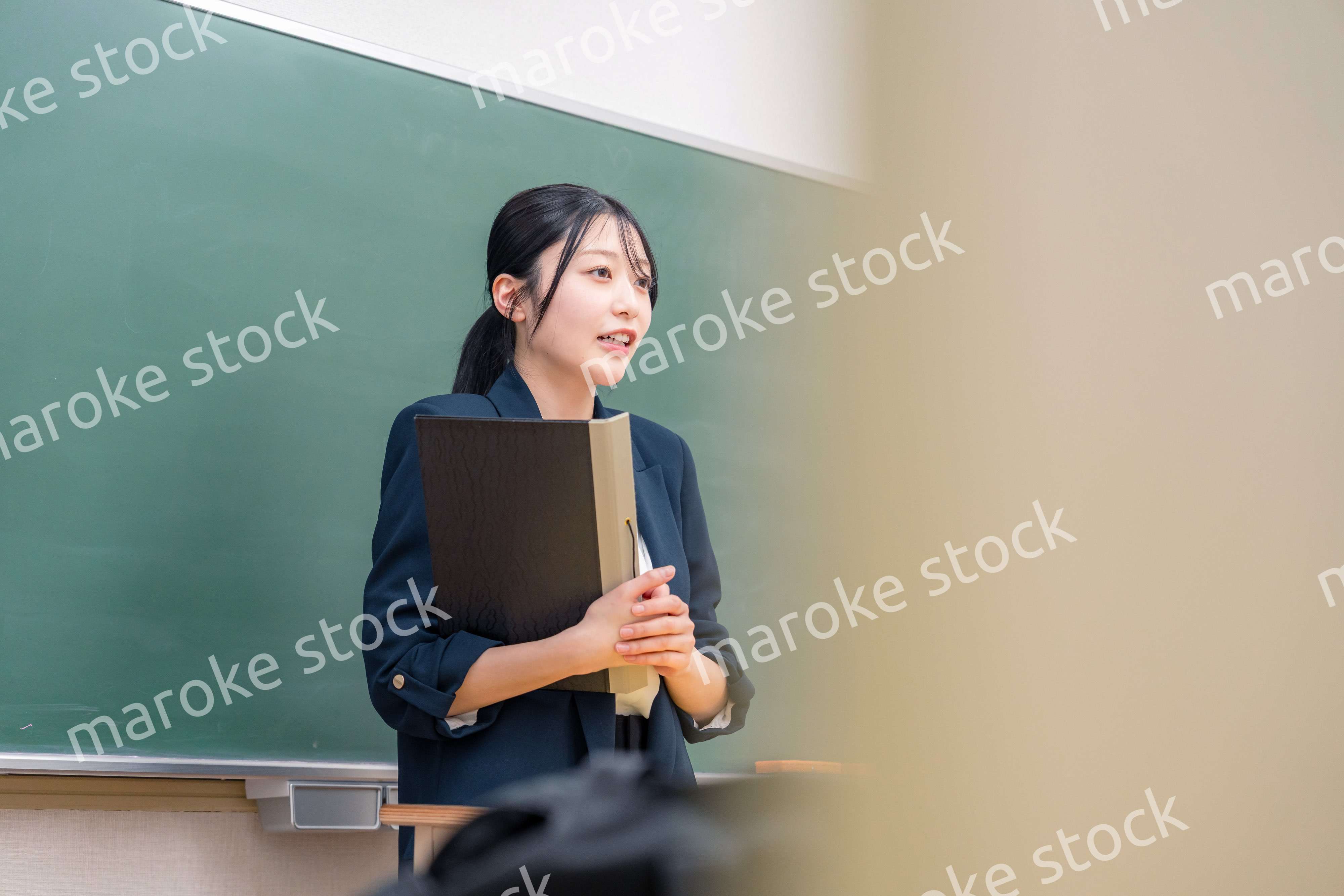 学校で教壇に立って授業をする若い女性教師