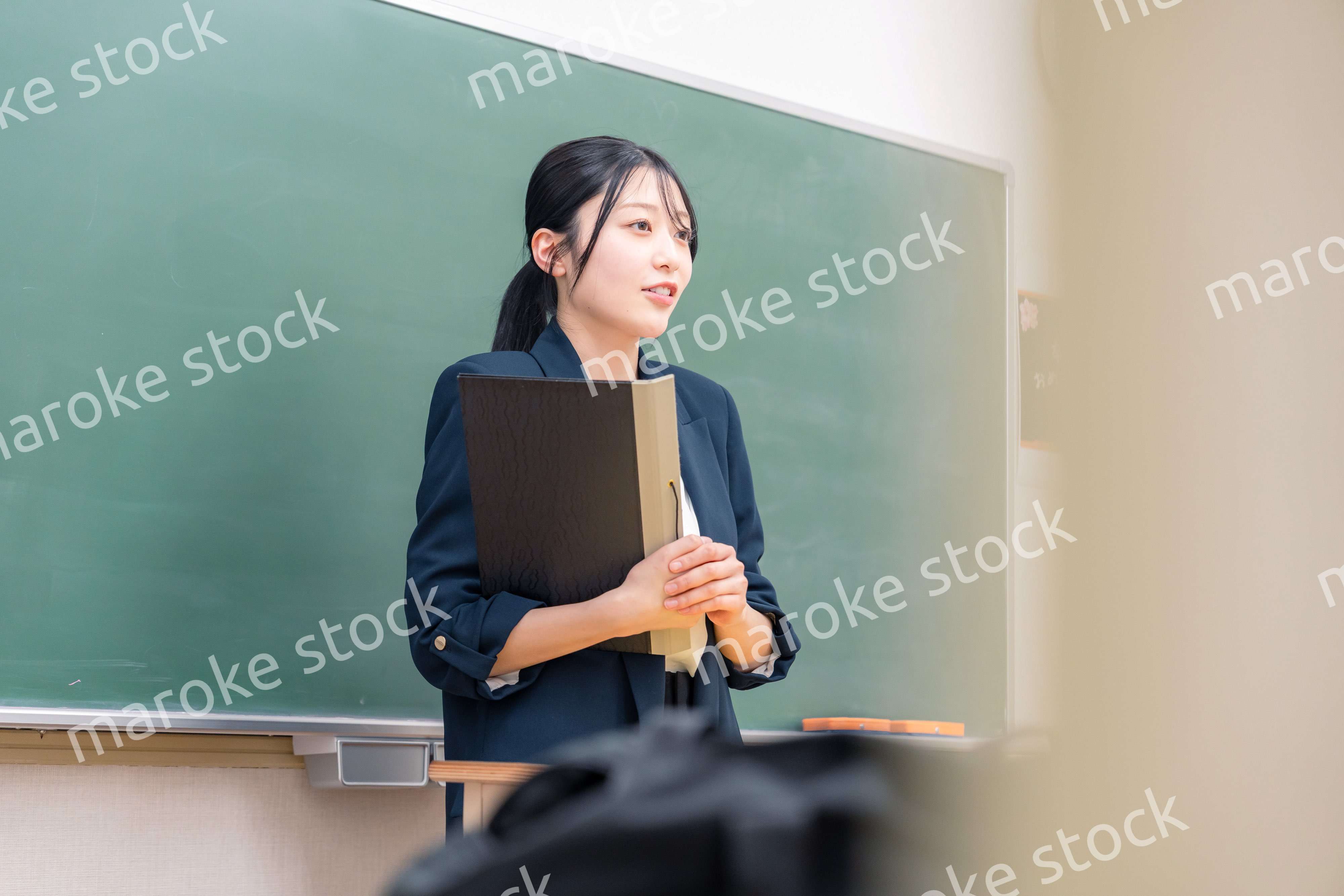 学校で教壇に立って授業をする若い女性教師