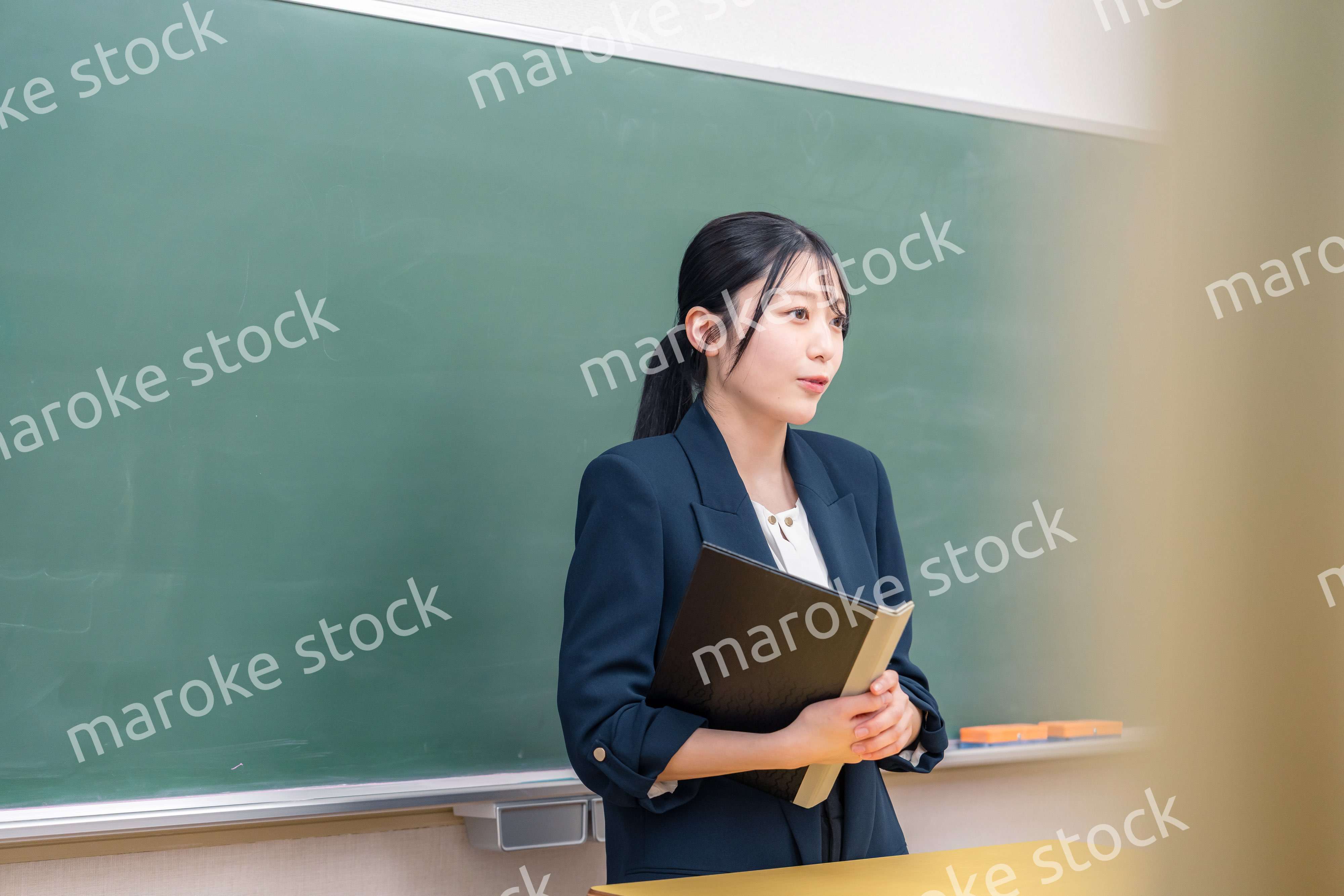 学校で教壇に立って授業をする若い女性教師