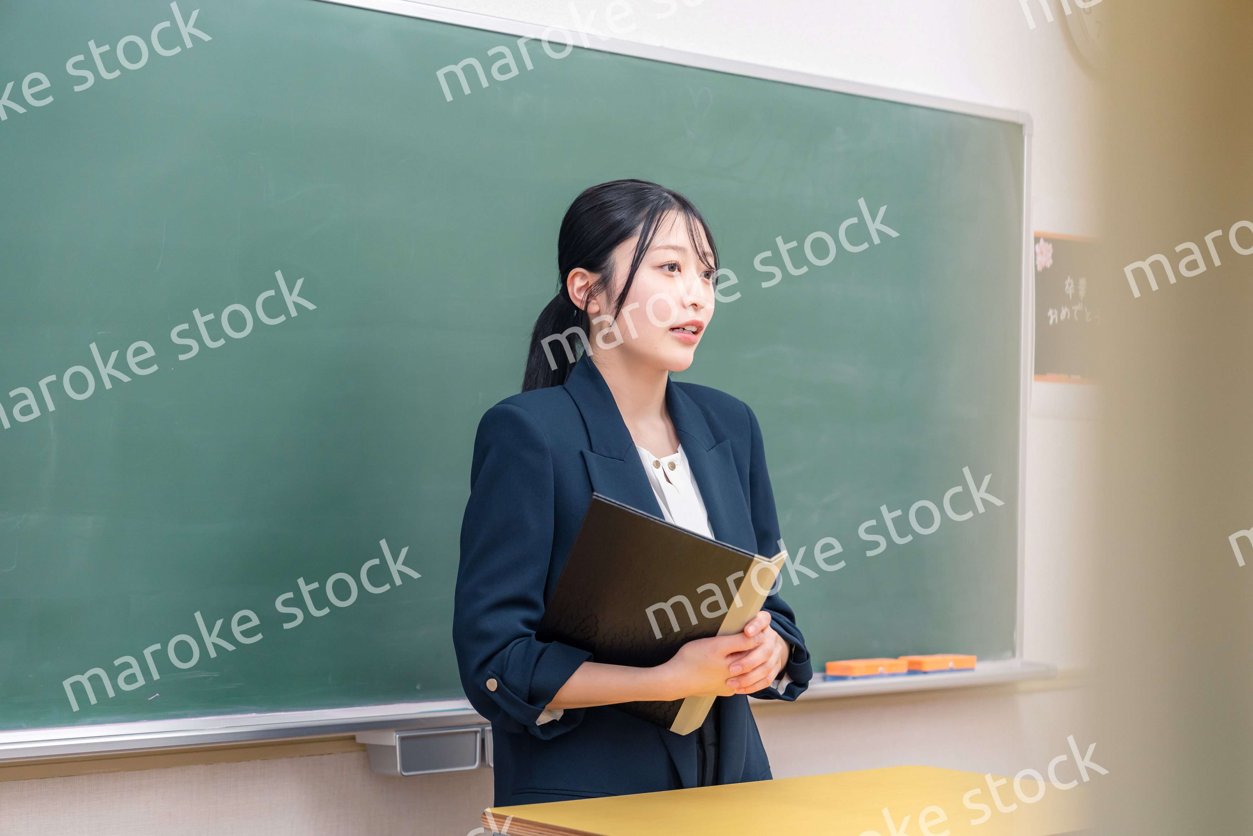 学校で教壇に立って授業をする若い女性教師