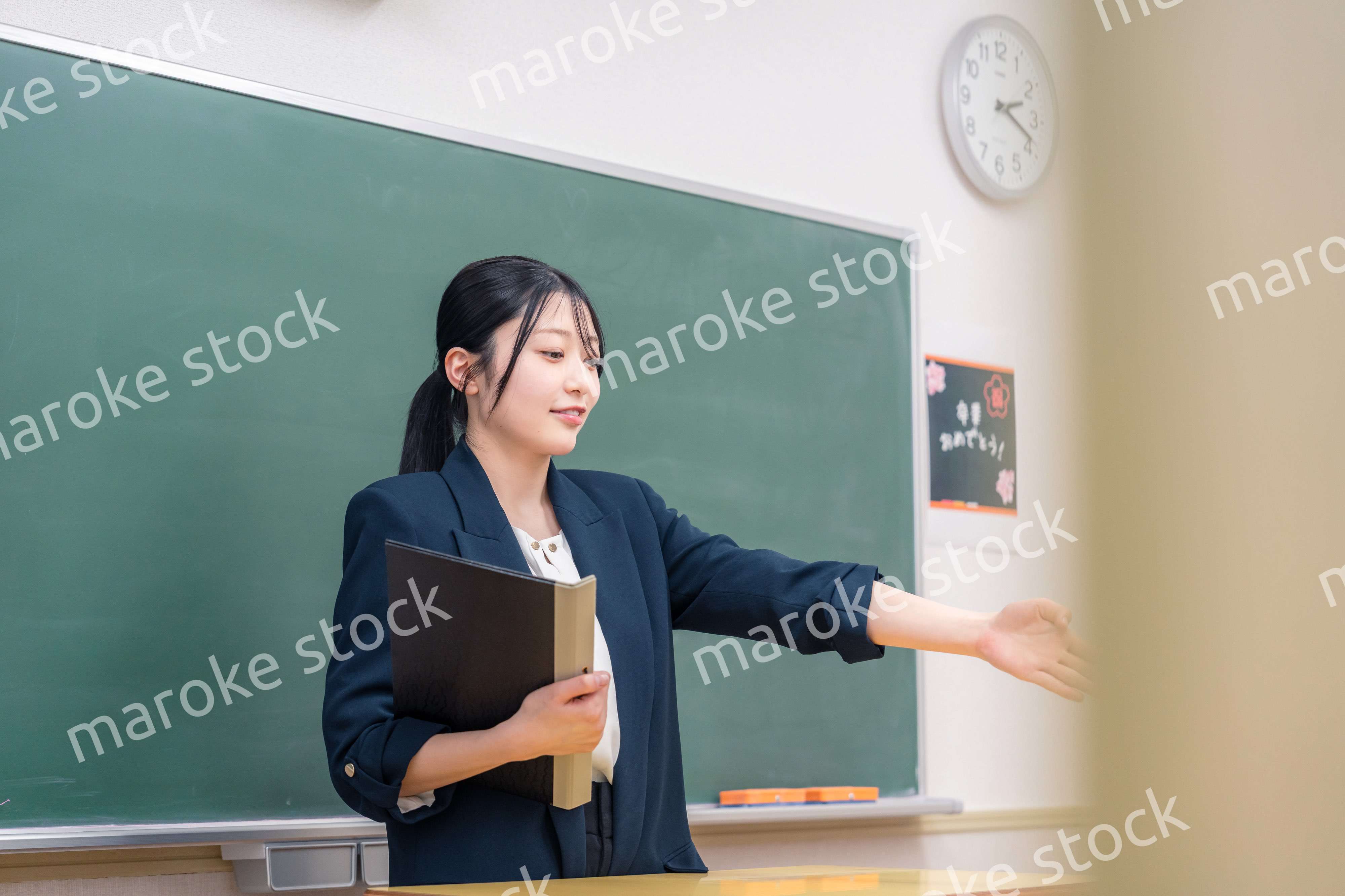 学校で教壇に立って授業をする若い女性教師