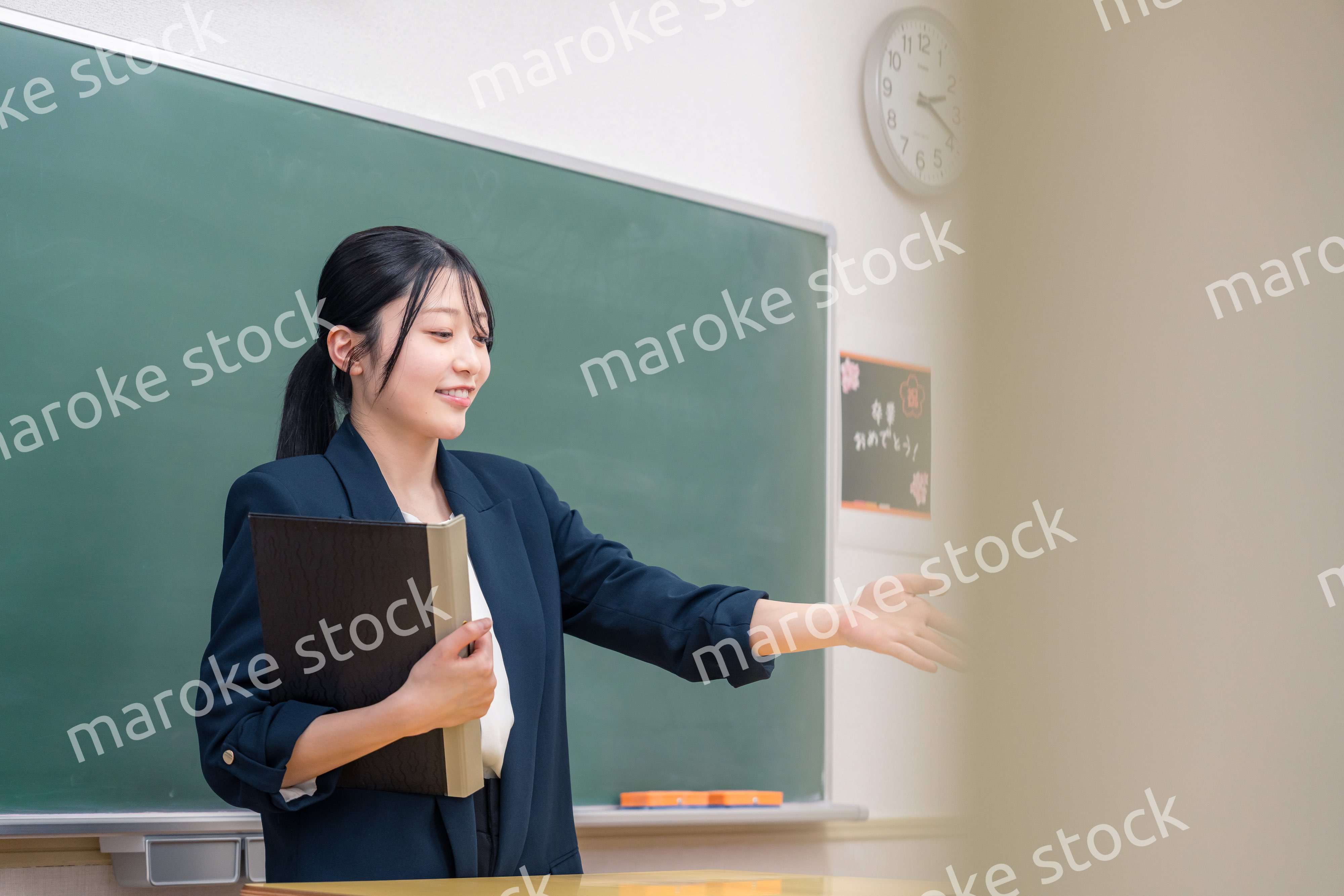 学校で教壇に立って授業をする若い女性教師