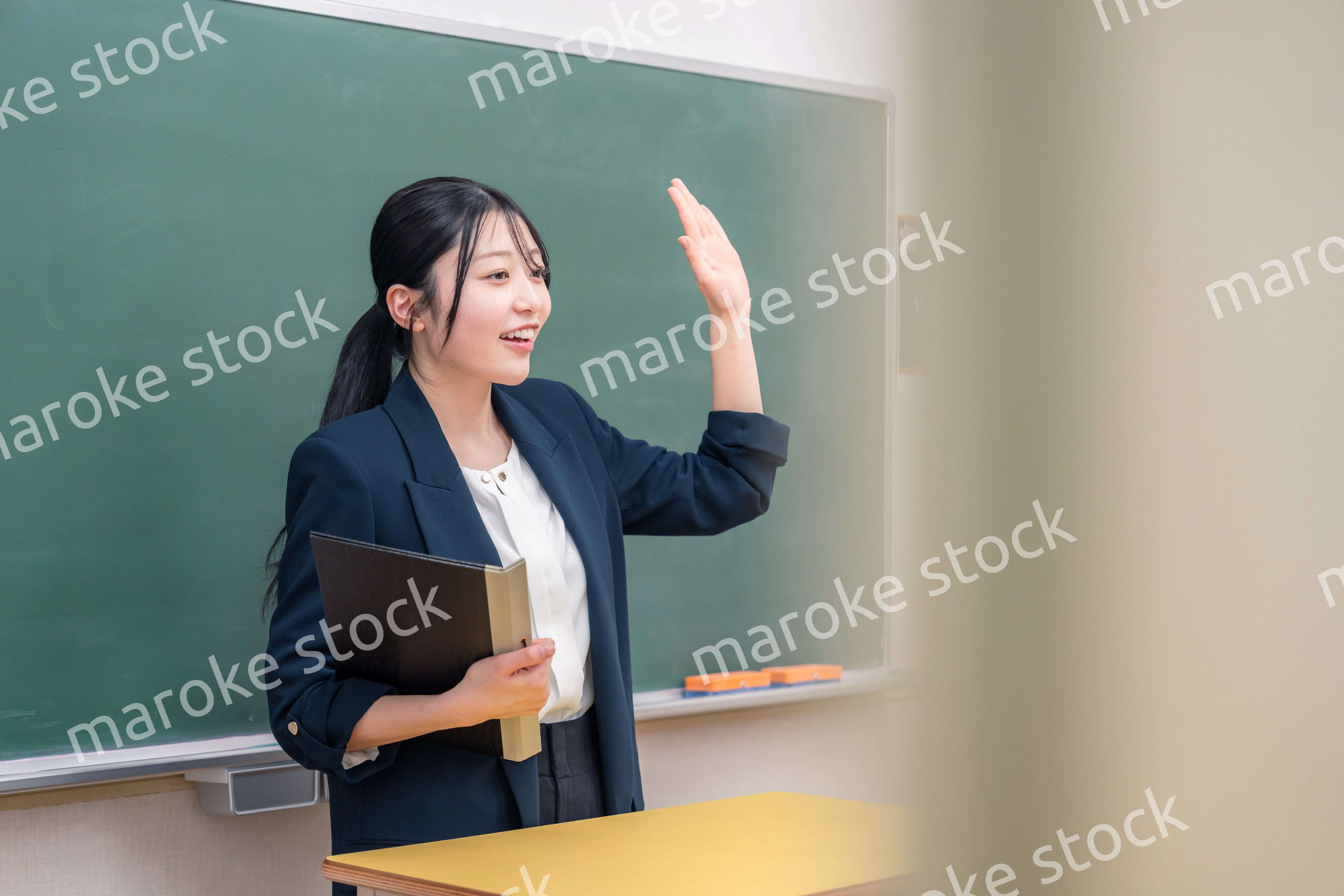 学校で教壇に立って授業をする若い女性教師