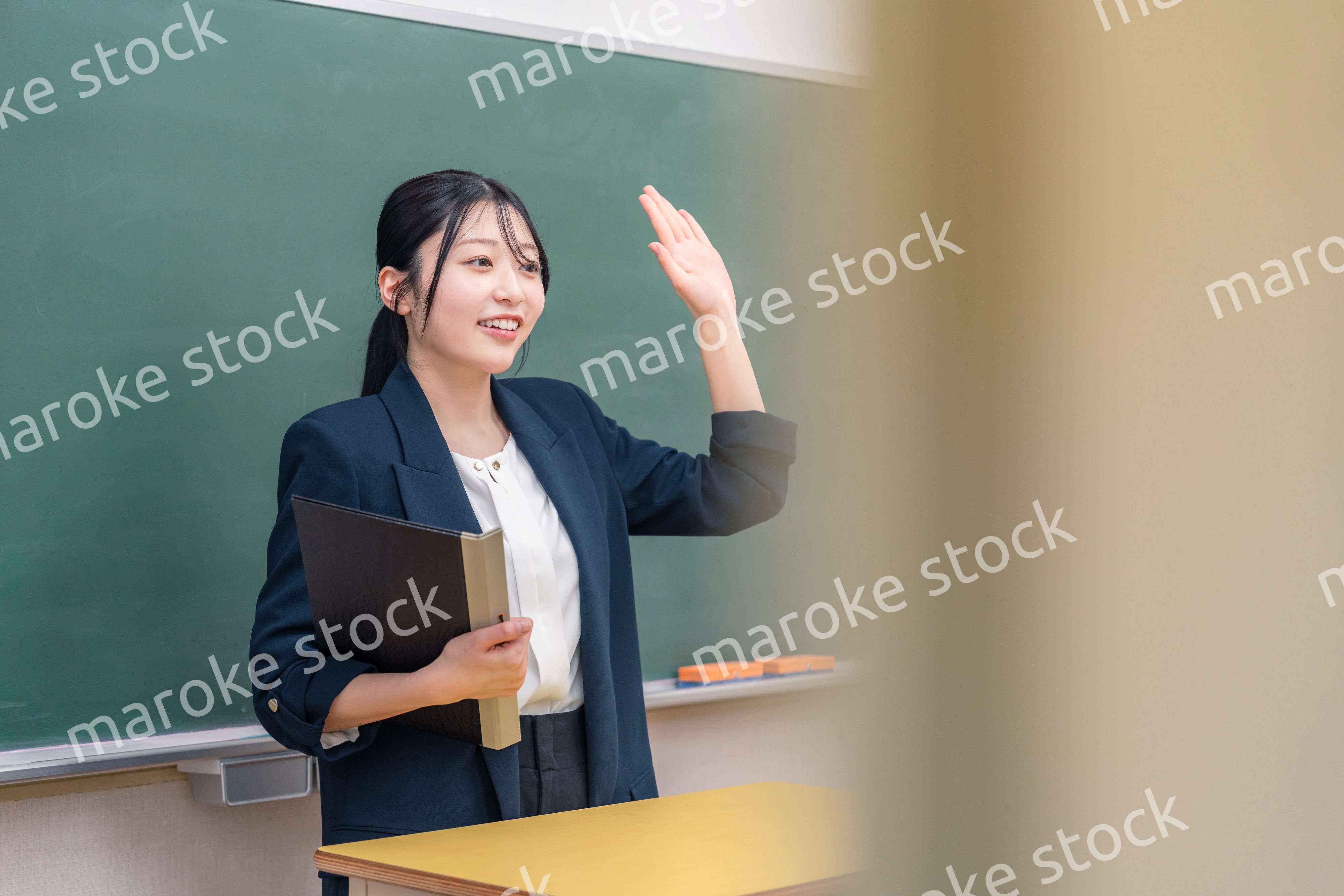 学校で教壇に立って授業をする若い女性教師