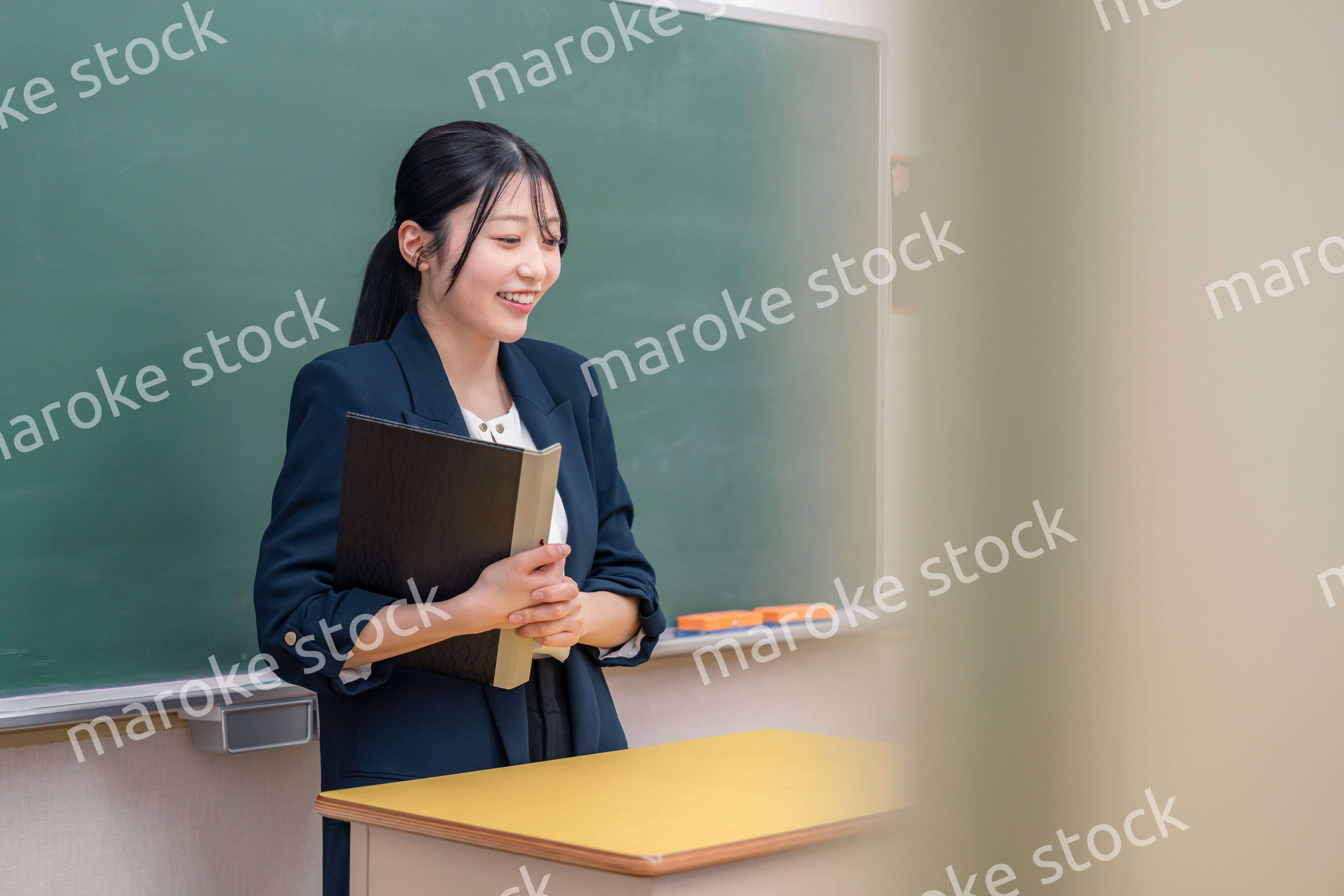 学校で教壇に立って授業をする若い女性教師