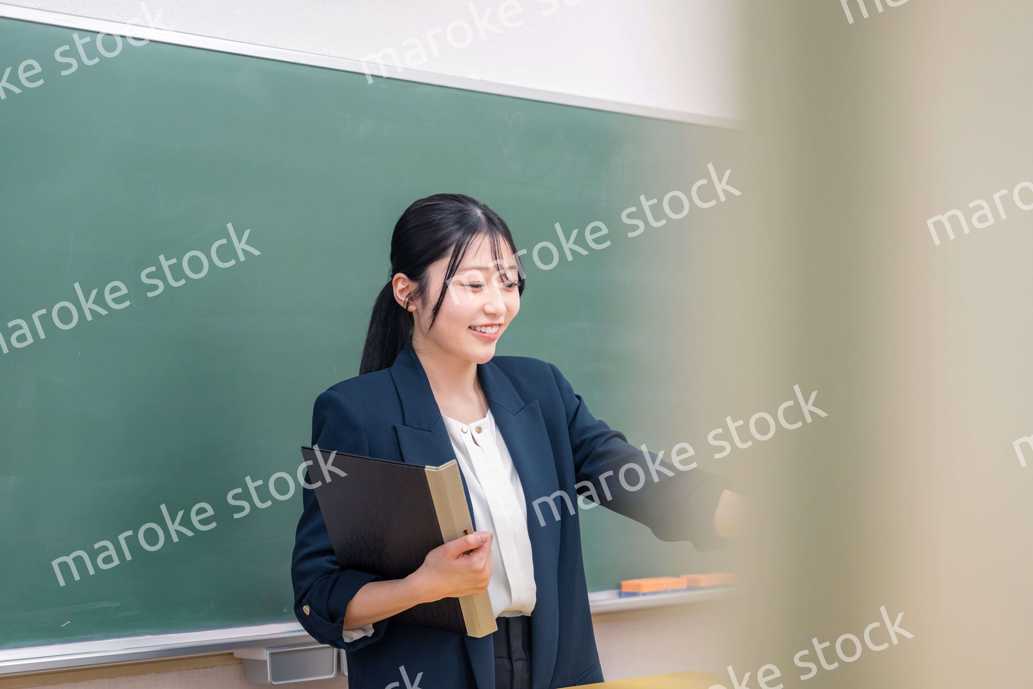 学校で教壇に立って授業をする若い女性教師