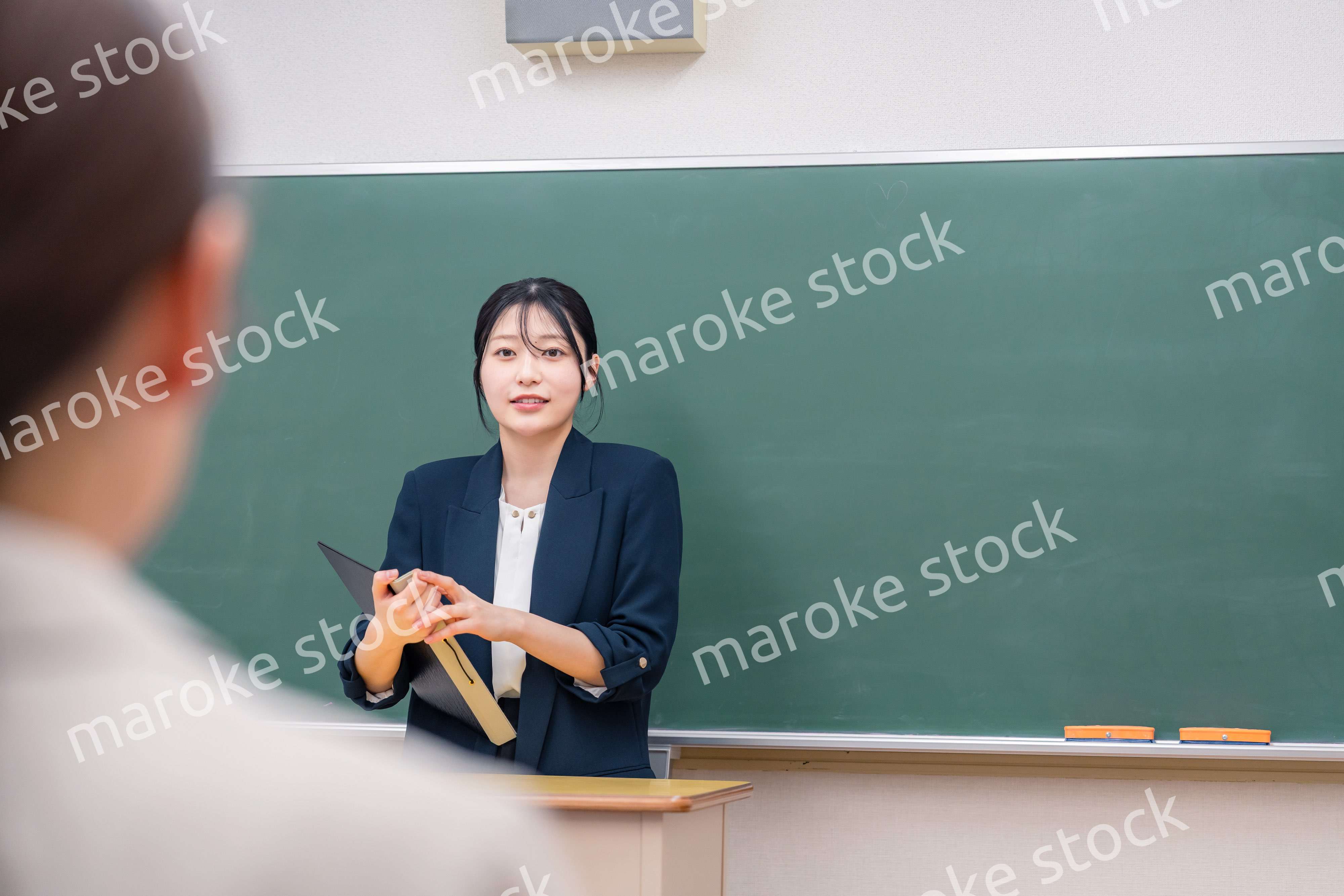 学校で教壇に立って授業をする若い女性教師