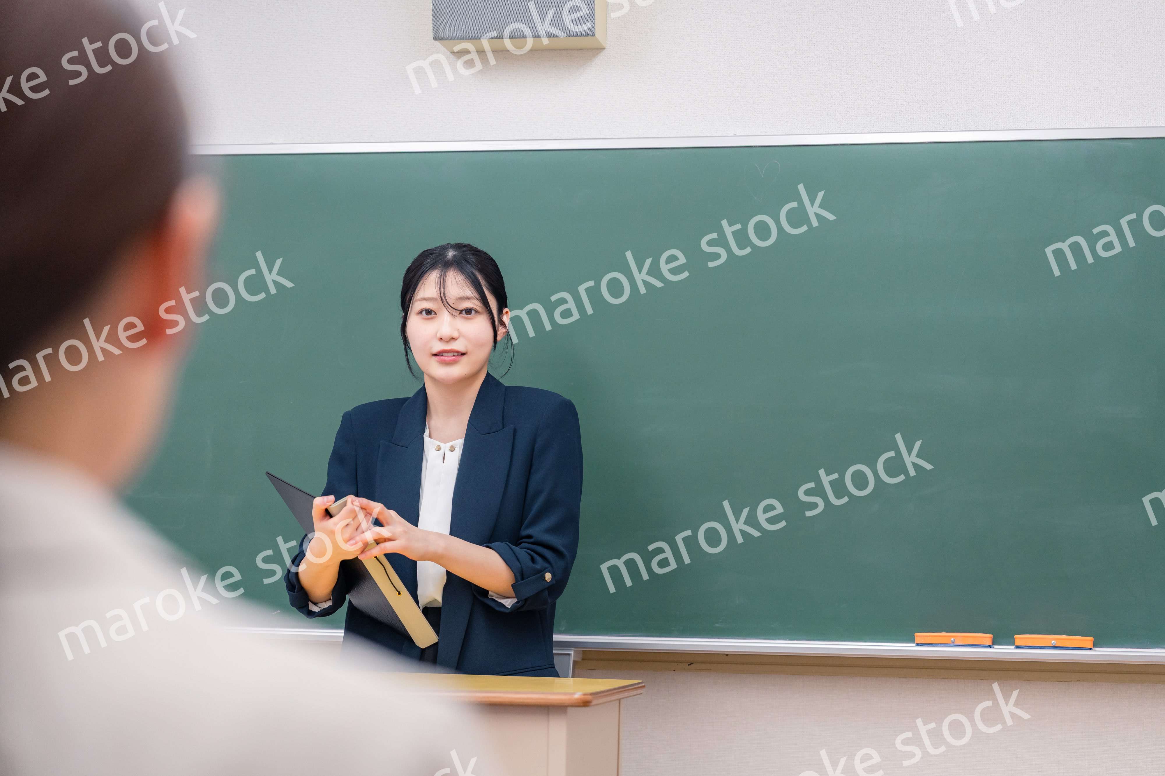 学校で教壇に立って授業をする若い女性教師