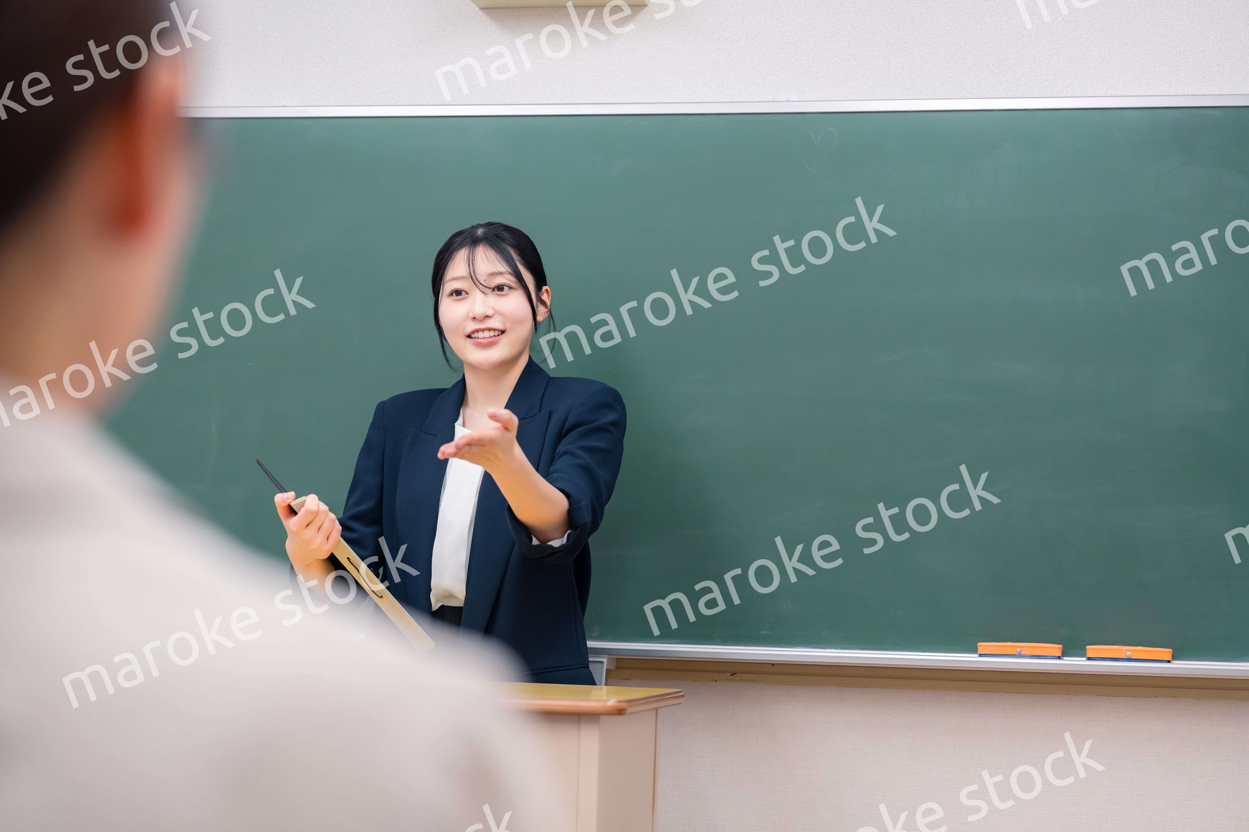 学校で教壇に立って授業をする若い女性教師