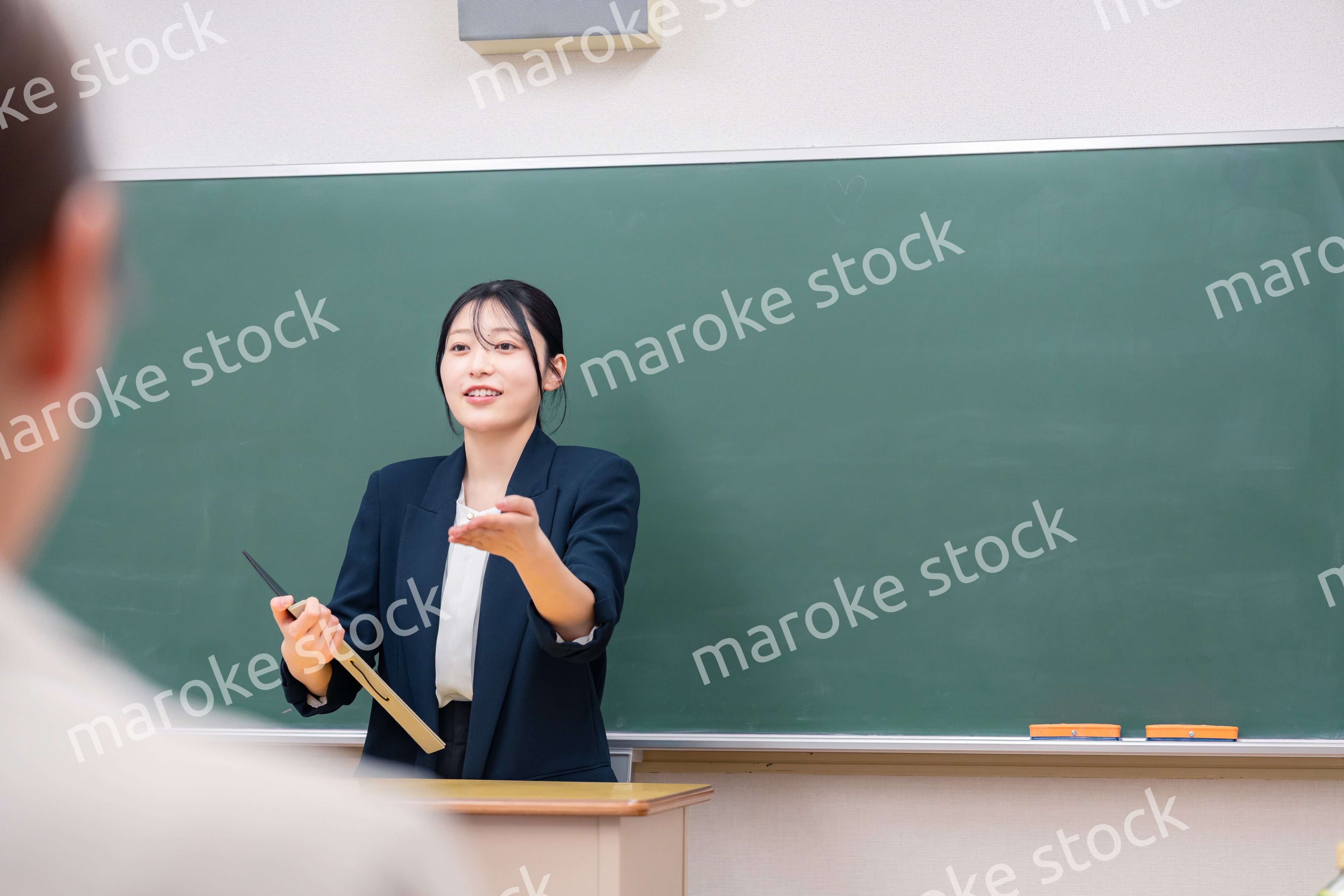 学校で教壇に立って授業をする若い女性教師