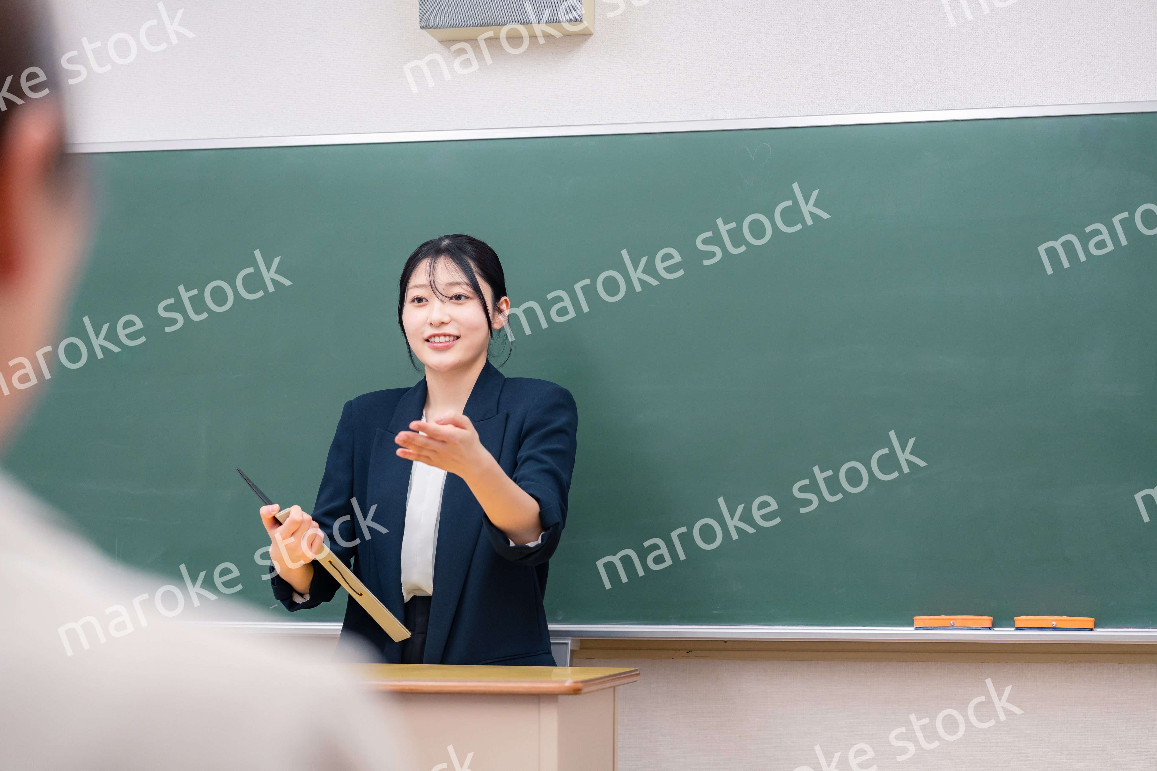学校で教壇に立って授業をする若い女性教師