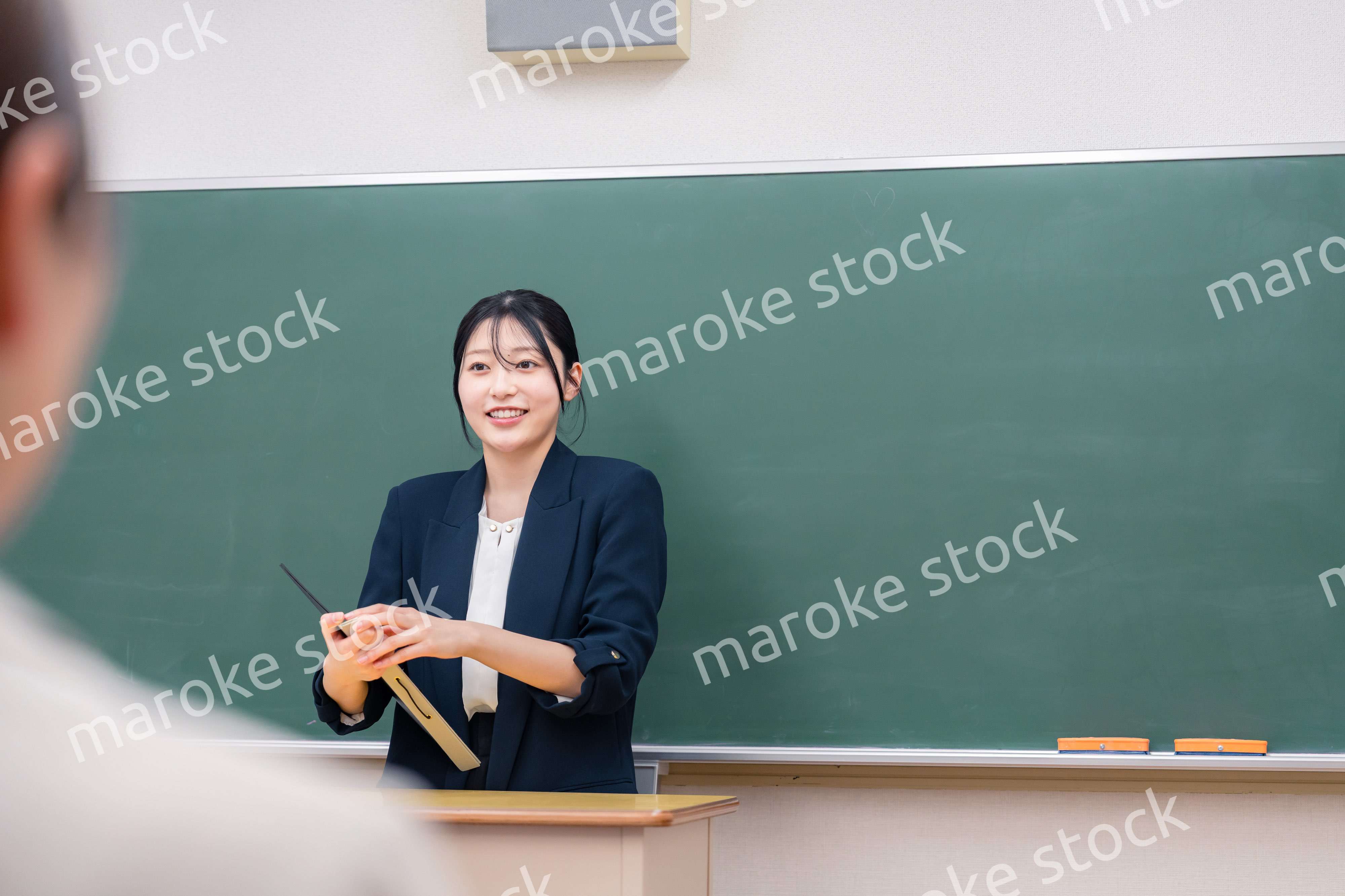 学校で教壇に立って授業をする若い女性教師