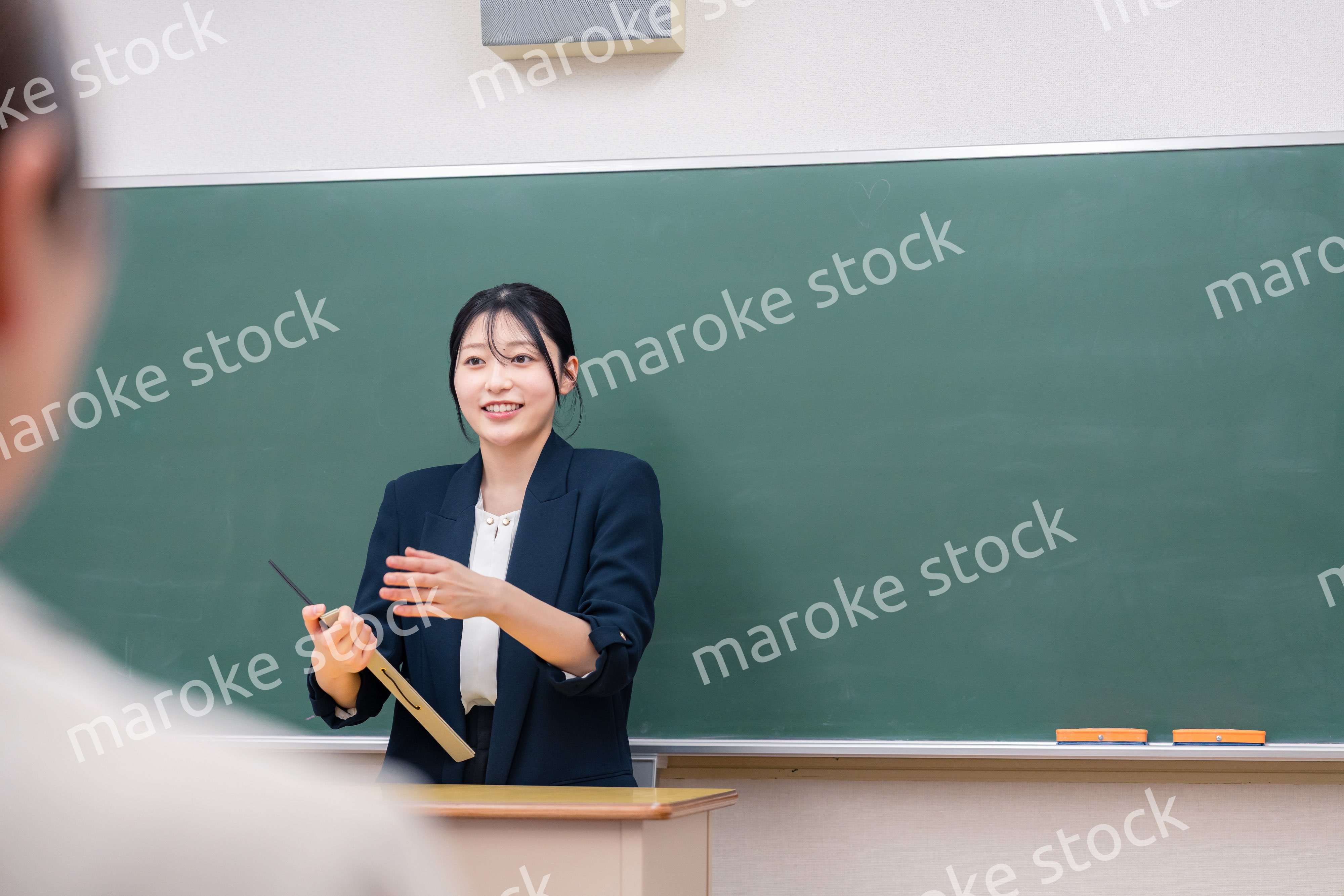 学校で教壇に立って授業をする若い女性教師