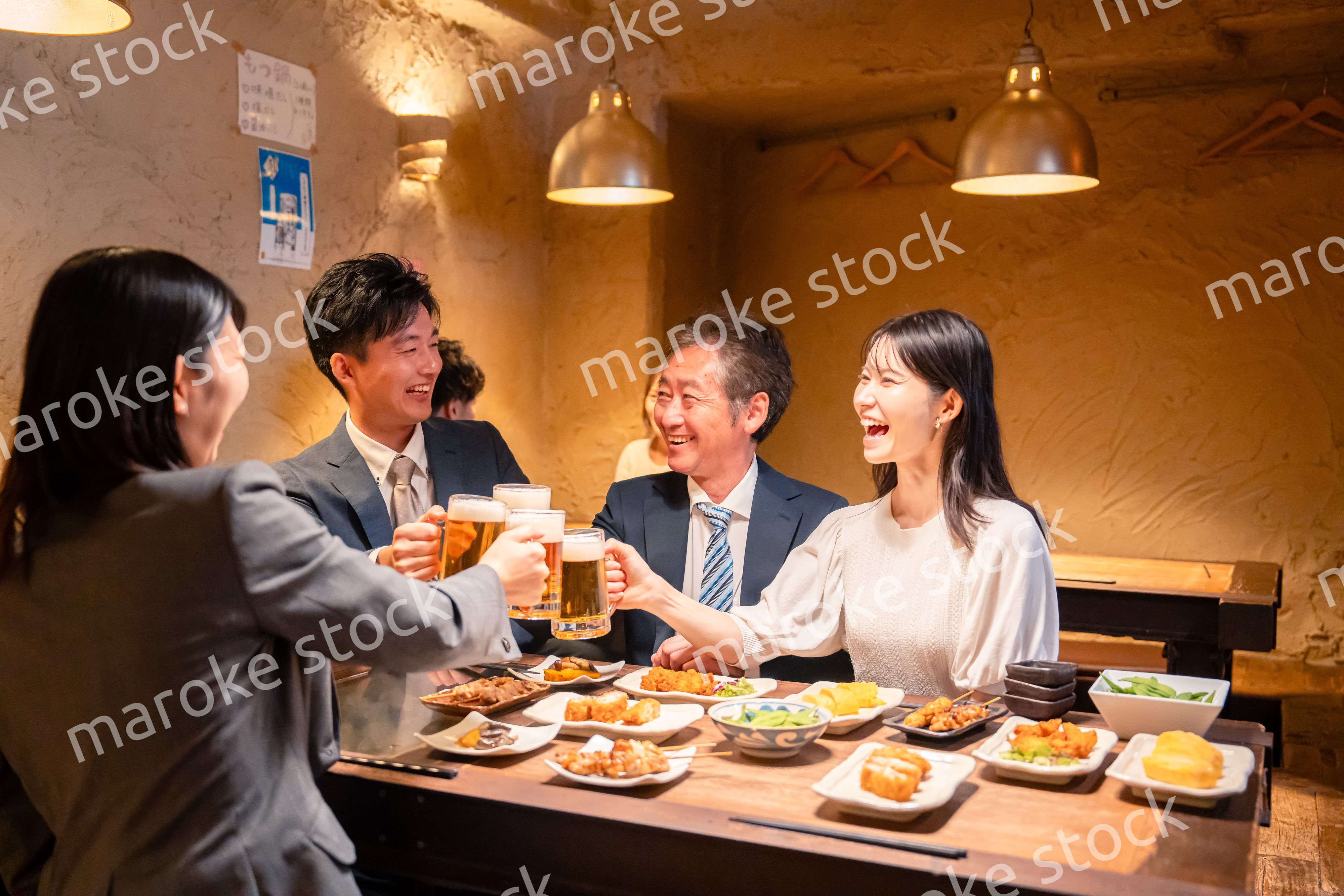 居酒屋で乾杯をする男女のビジネスパーソン