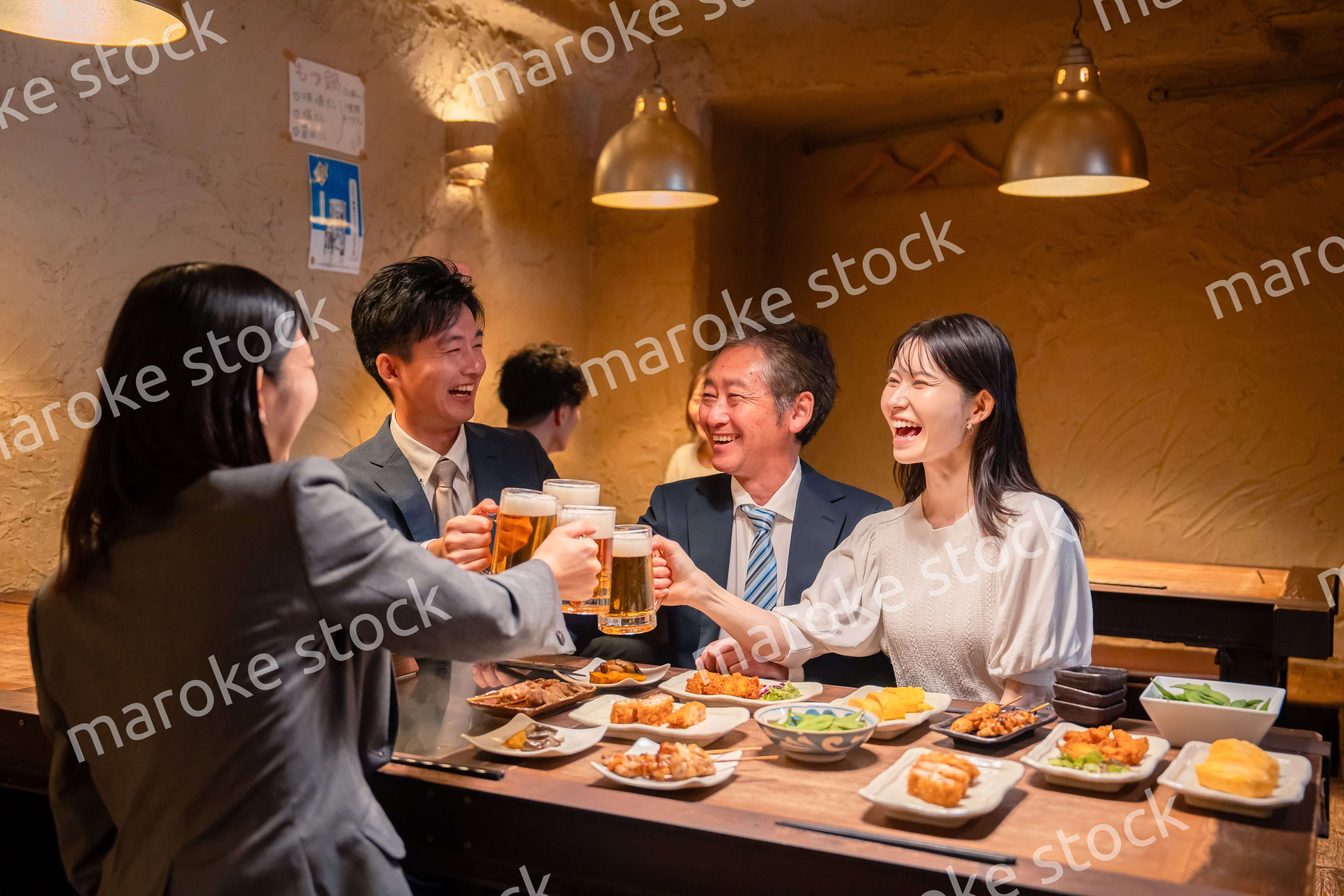 居酒屋で乾杯をする男女のビジネスパーソン