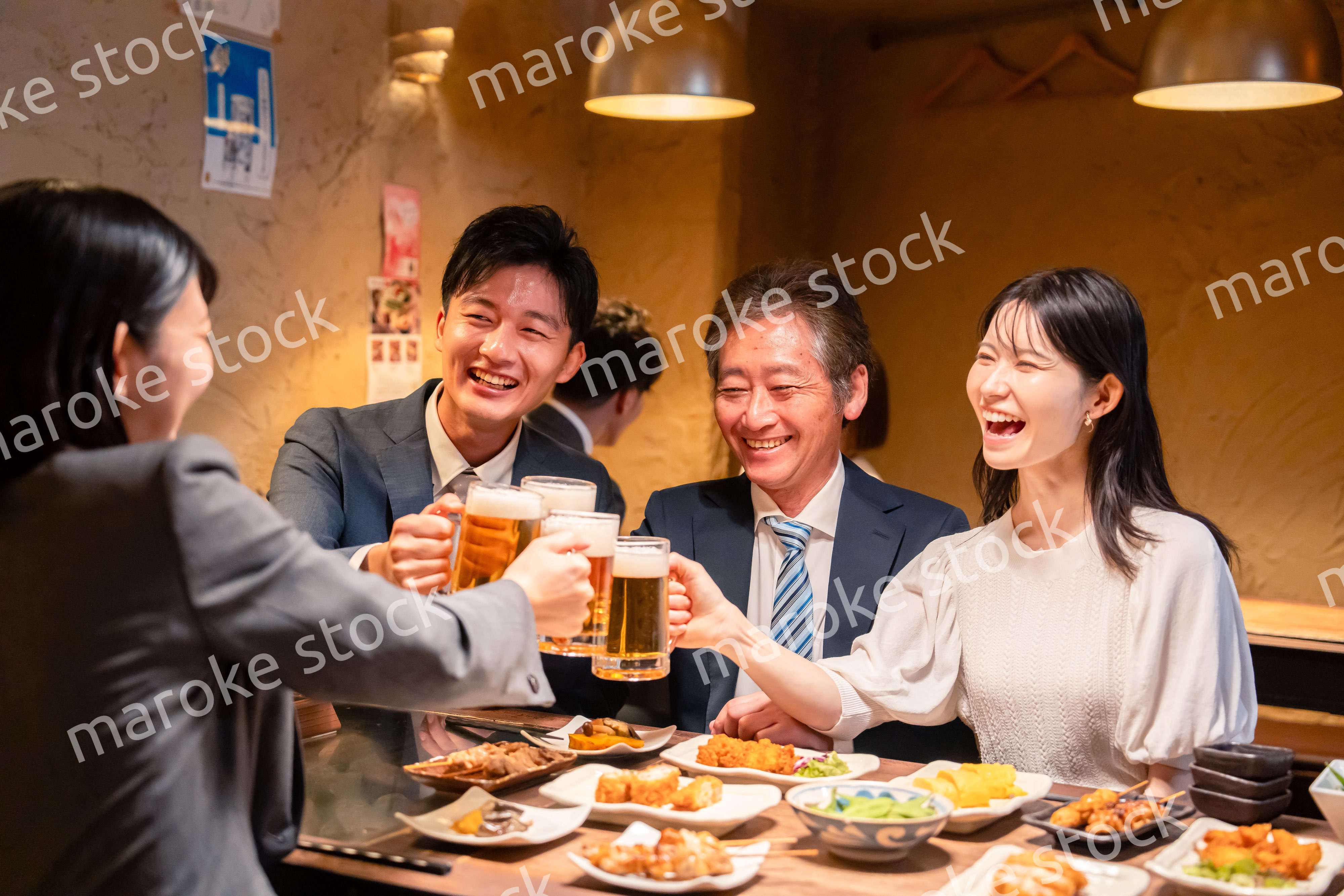 居酒屋で乾杯をする男女のビジネスパーソン