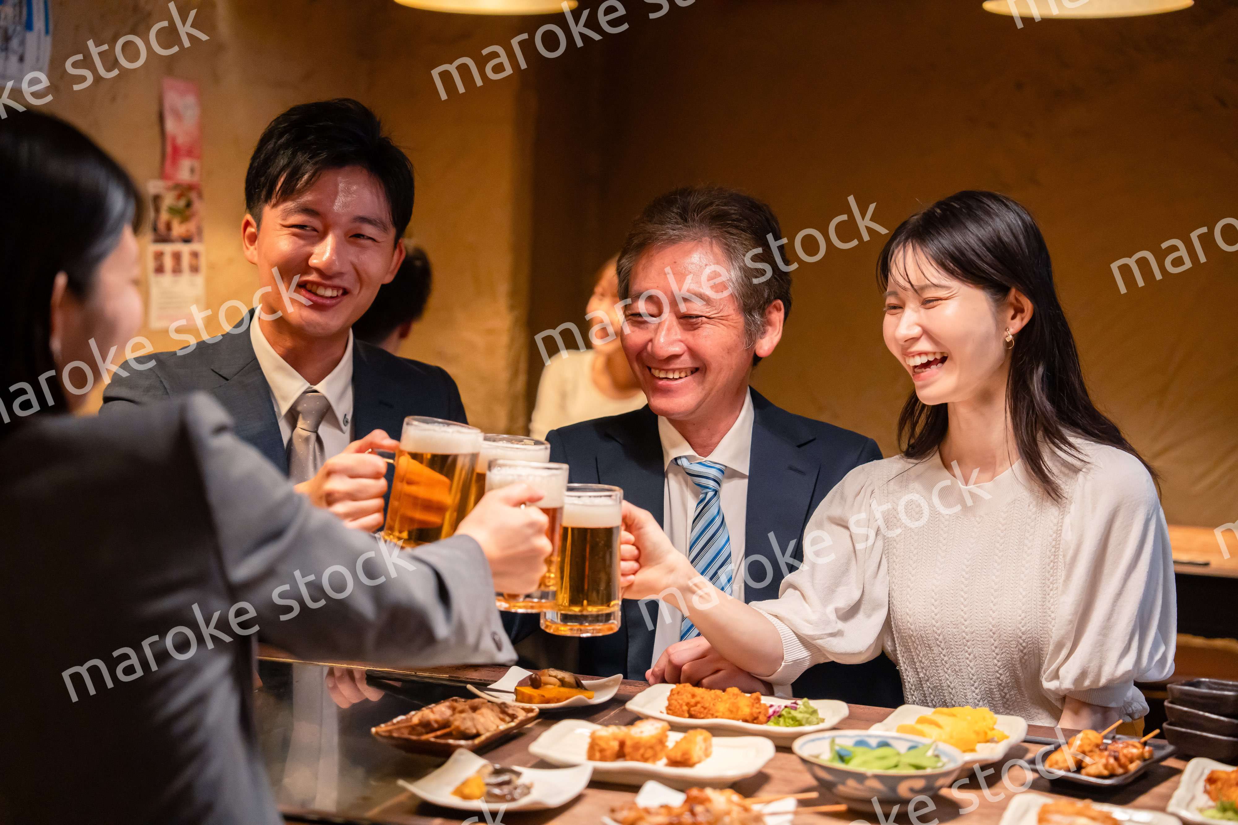 居酒屋で乾杯をする男女のビジネスパーソン