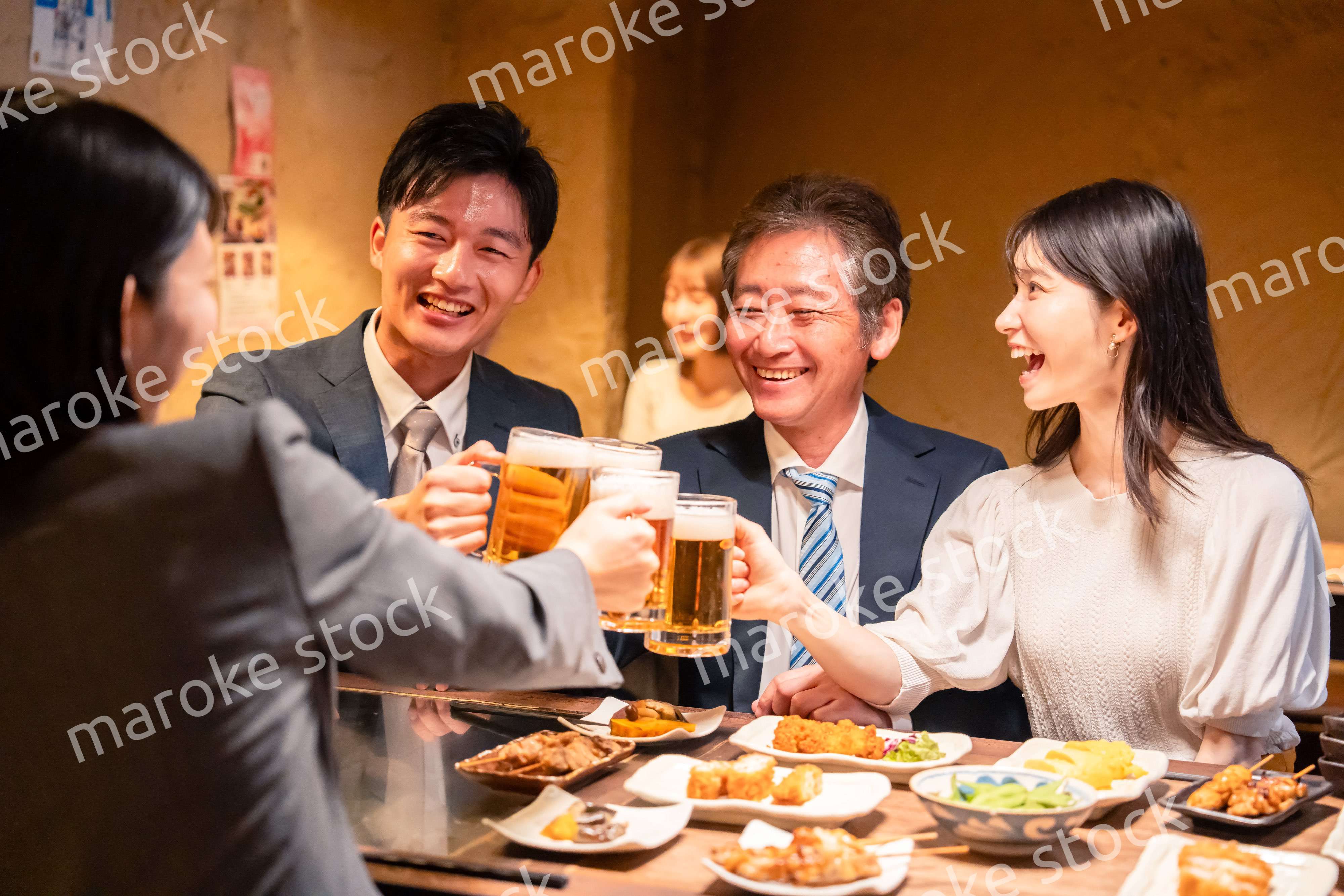 居酒屋で乾杯をする男女のビジネスパーソン