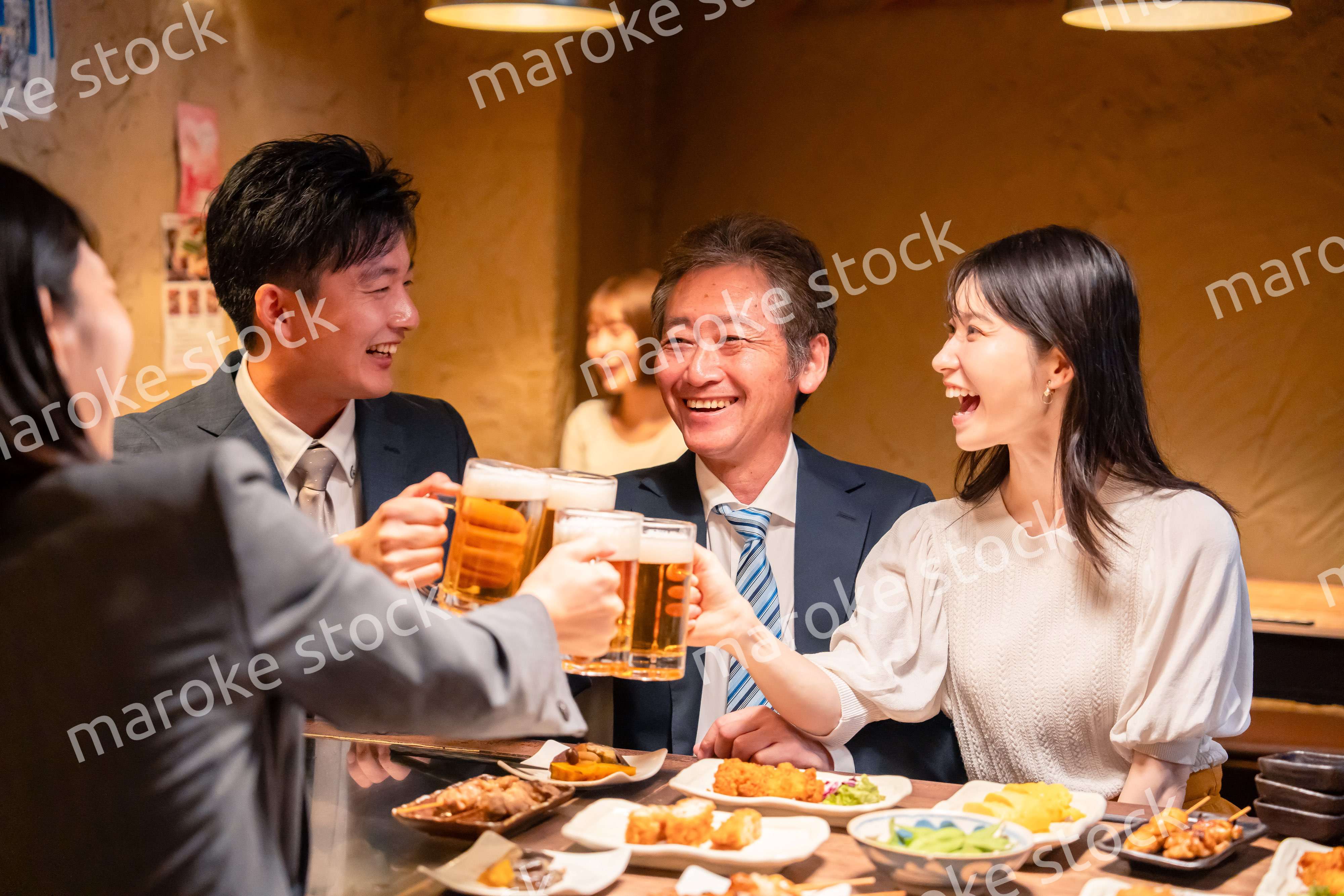 居酒屋で乾杯をする男女のビジネスパーソン