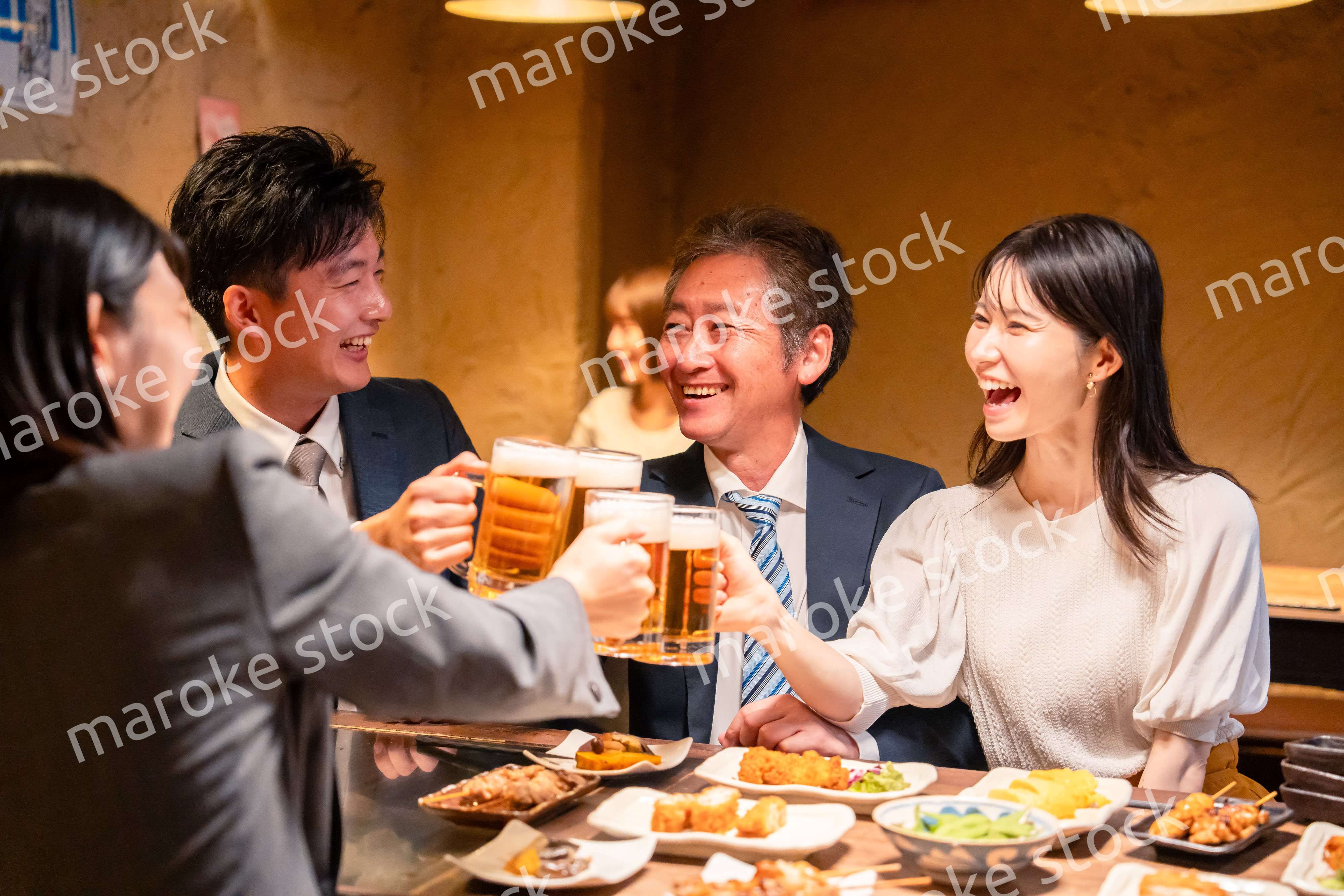 居酒屋で乾杯をする男女のビジネスパーソン