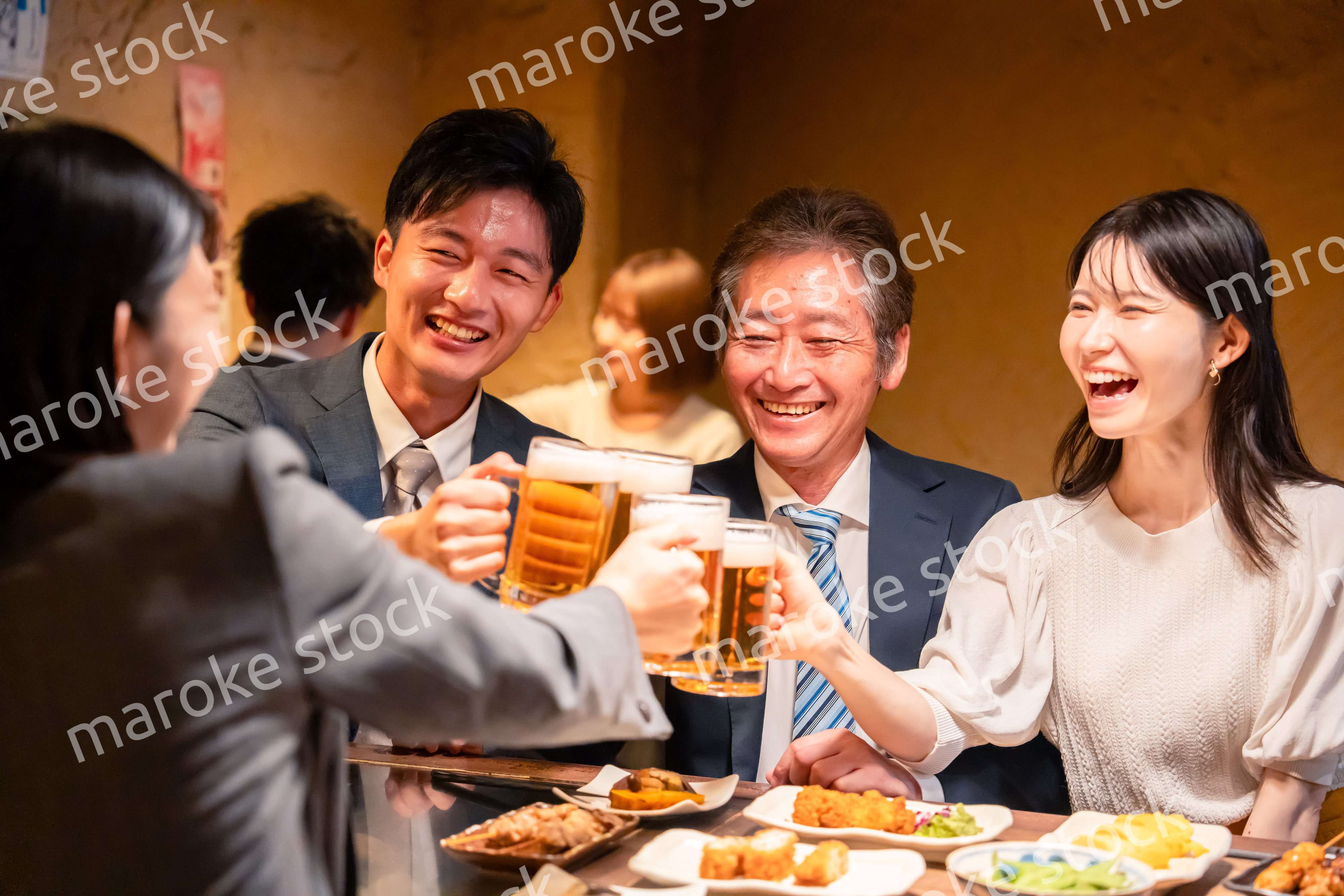 居酒屋で乾杯をする男女のビジネスパーソン