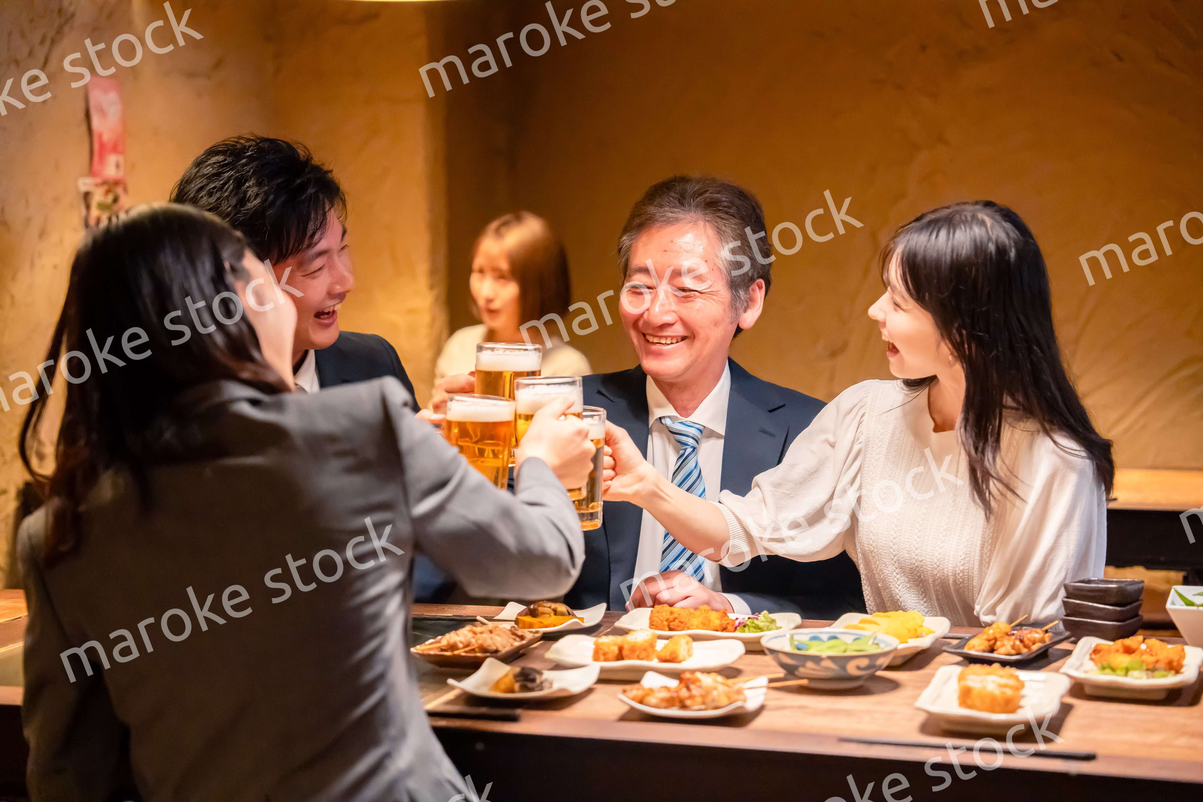 居酒屋で乾杯をする男女のビジネスパーソン