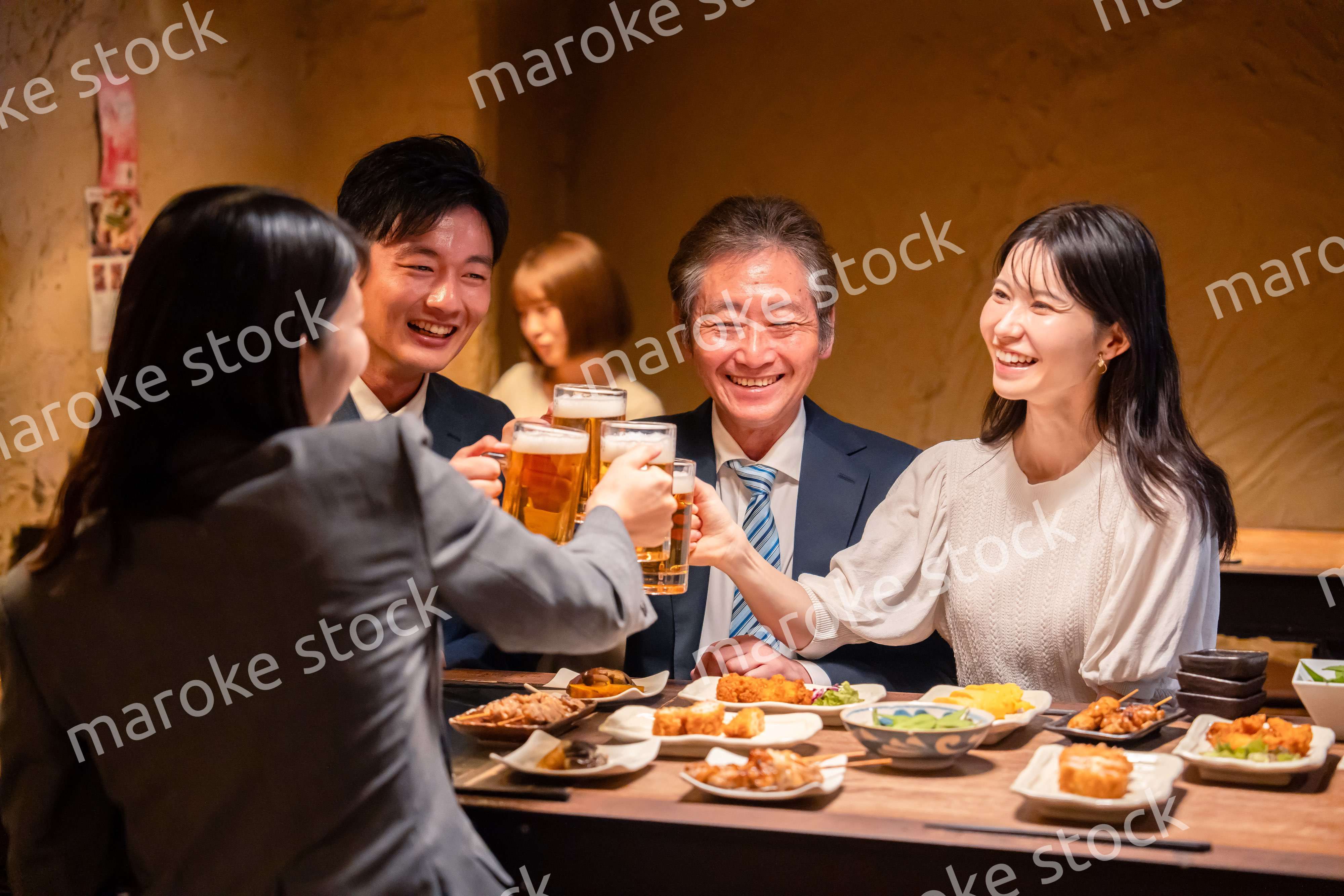 居酒屋で乾杯をする男女のビジネスパーソン