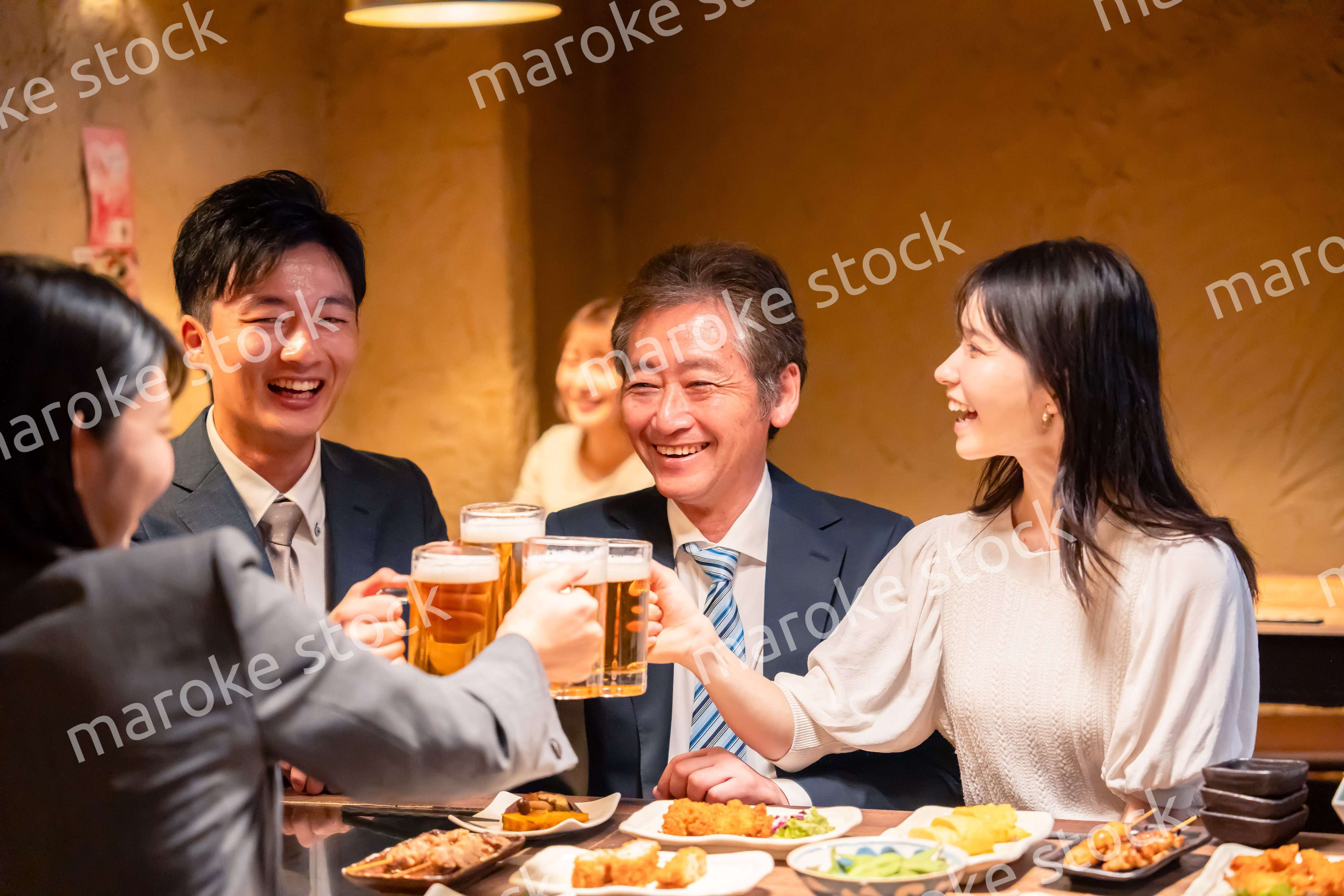 居酒屋で乾杯をする男女のビジネスパーソン