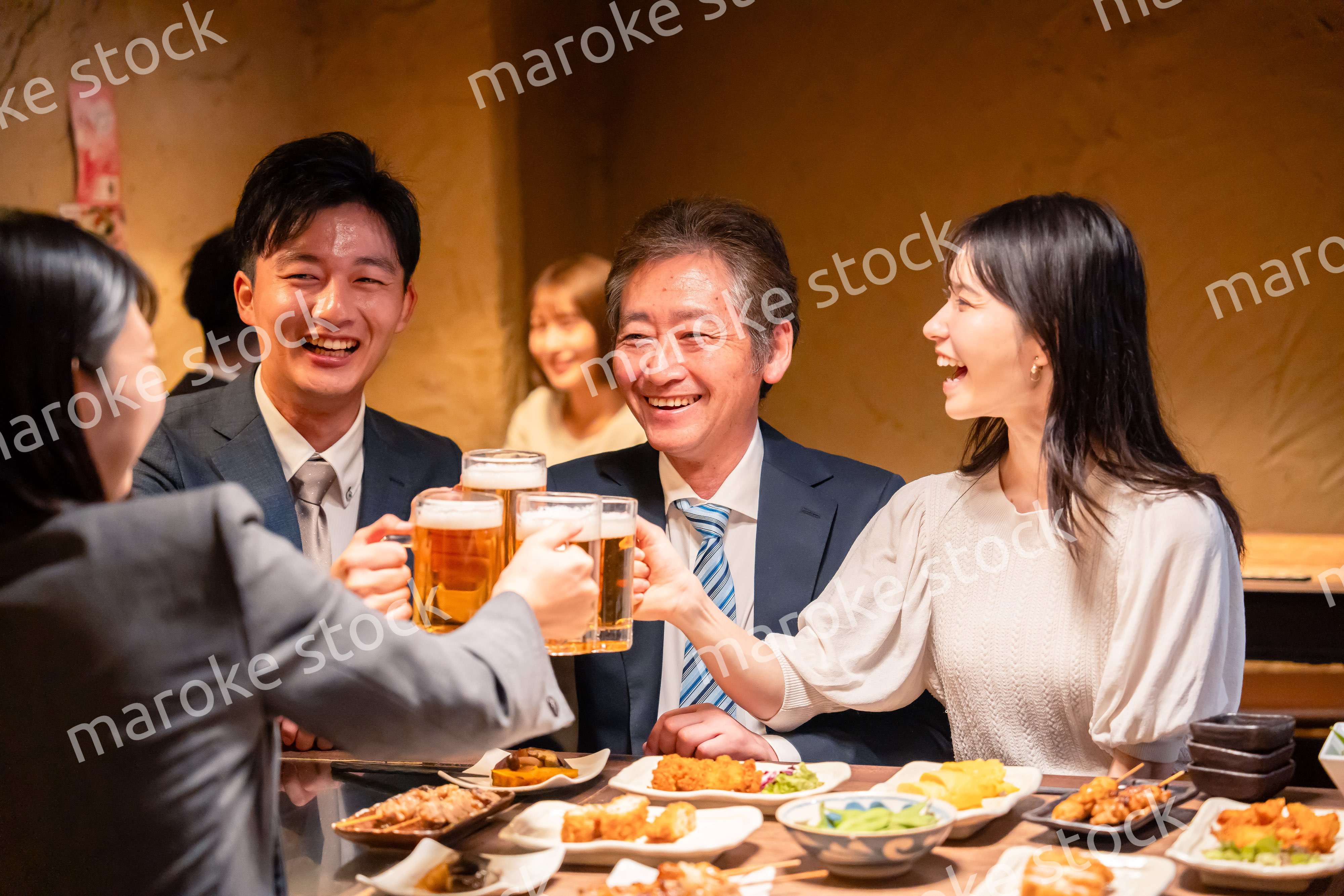 居酒屋で乾杯をする男女のビジネスパーソン