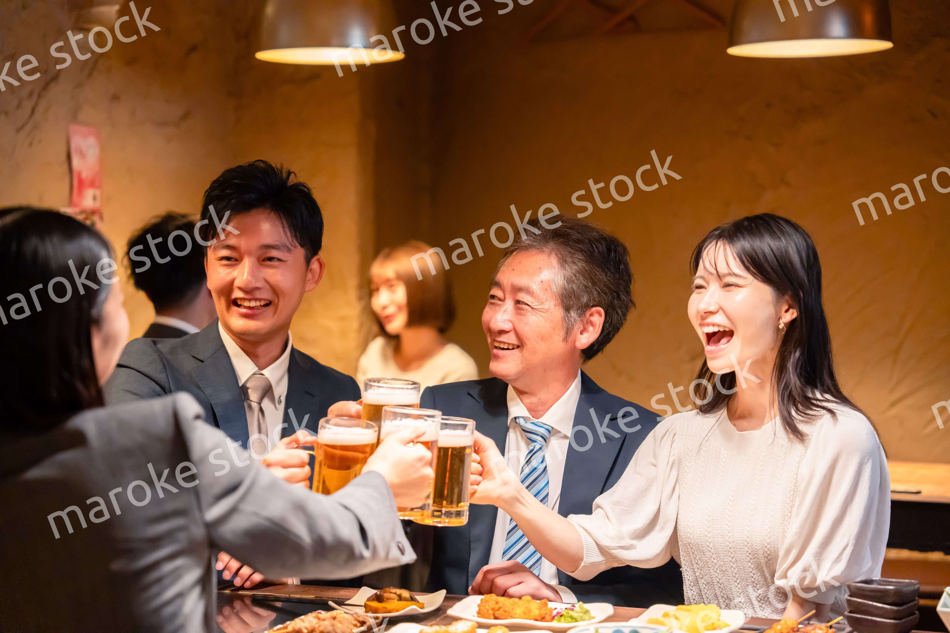 居酒屋で乾杯をする男女のビジネスパーソン