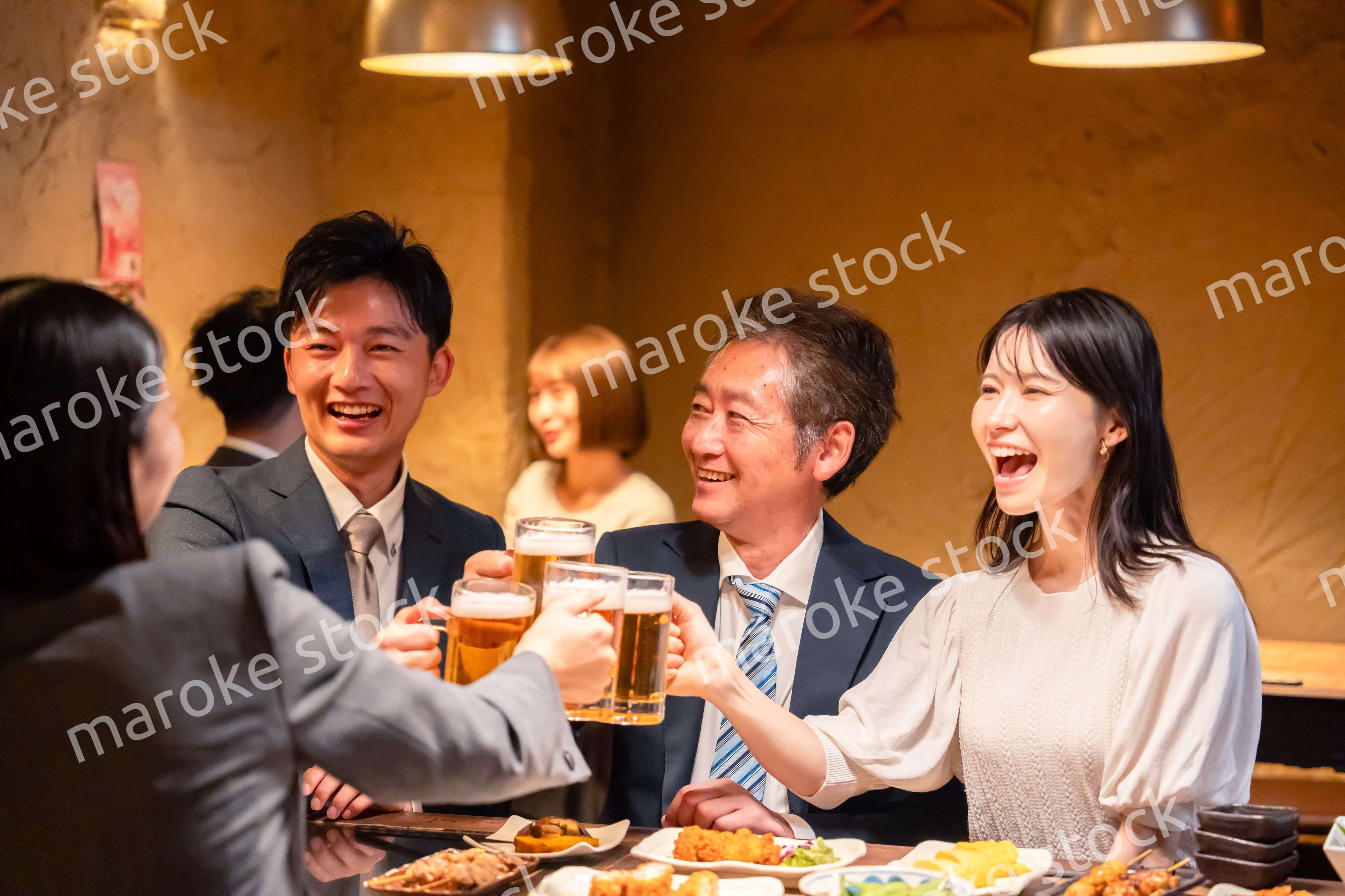 居酒屋で乾杯をする男女のビジネスパーソン