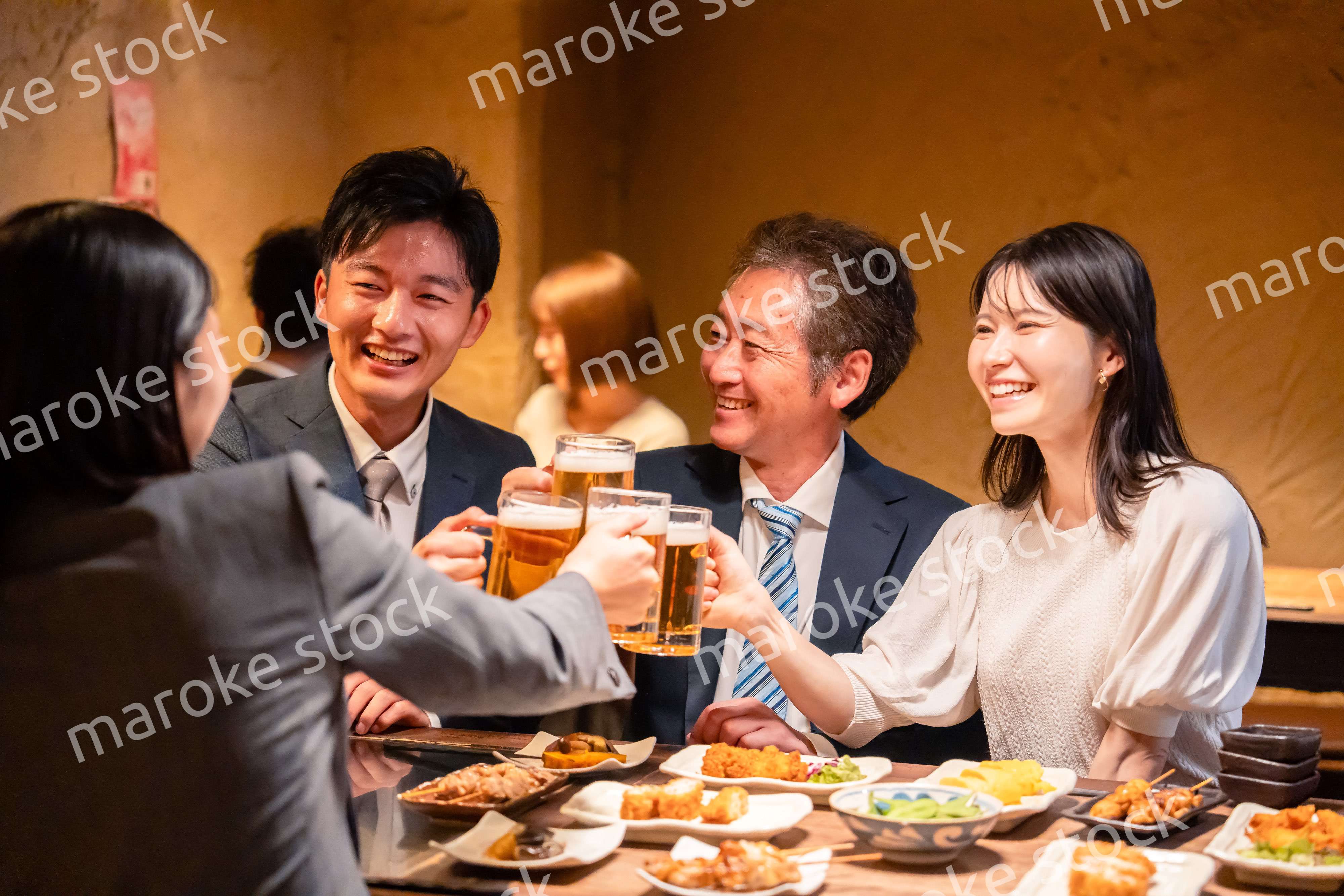 居酒屋で乾杯をする男女のビジネスパーソン