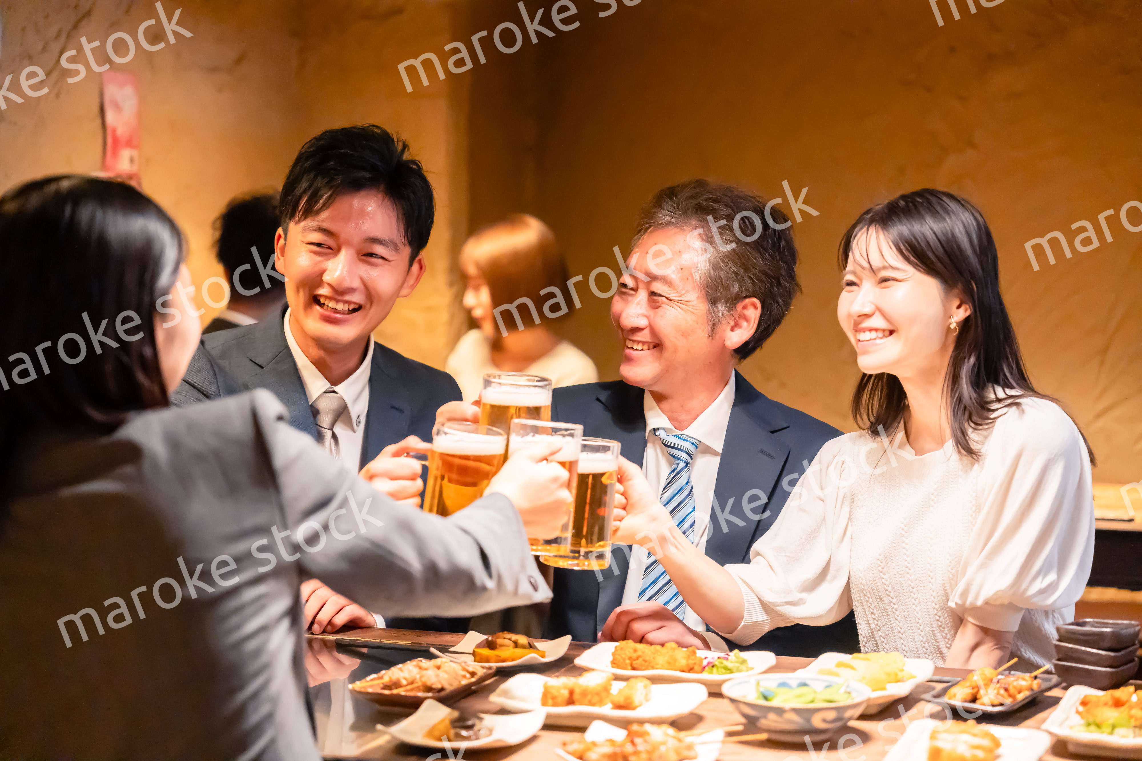 居酒屋で乾杯をする男女のビジネスパーソン