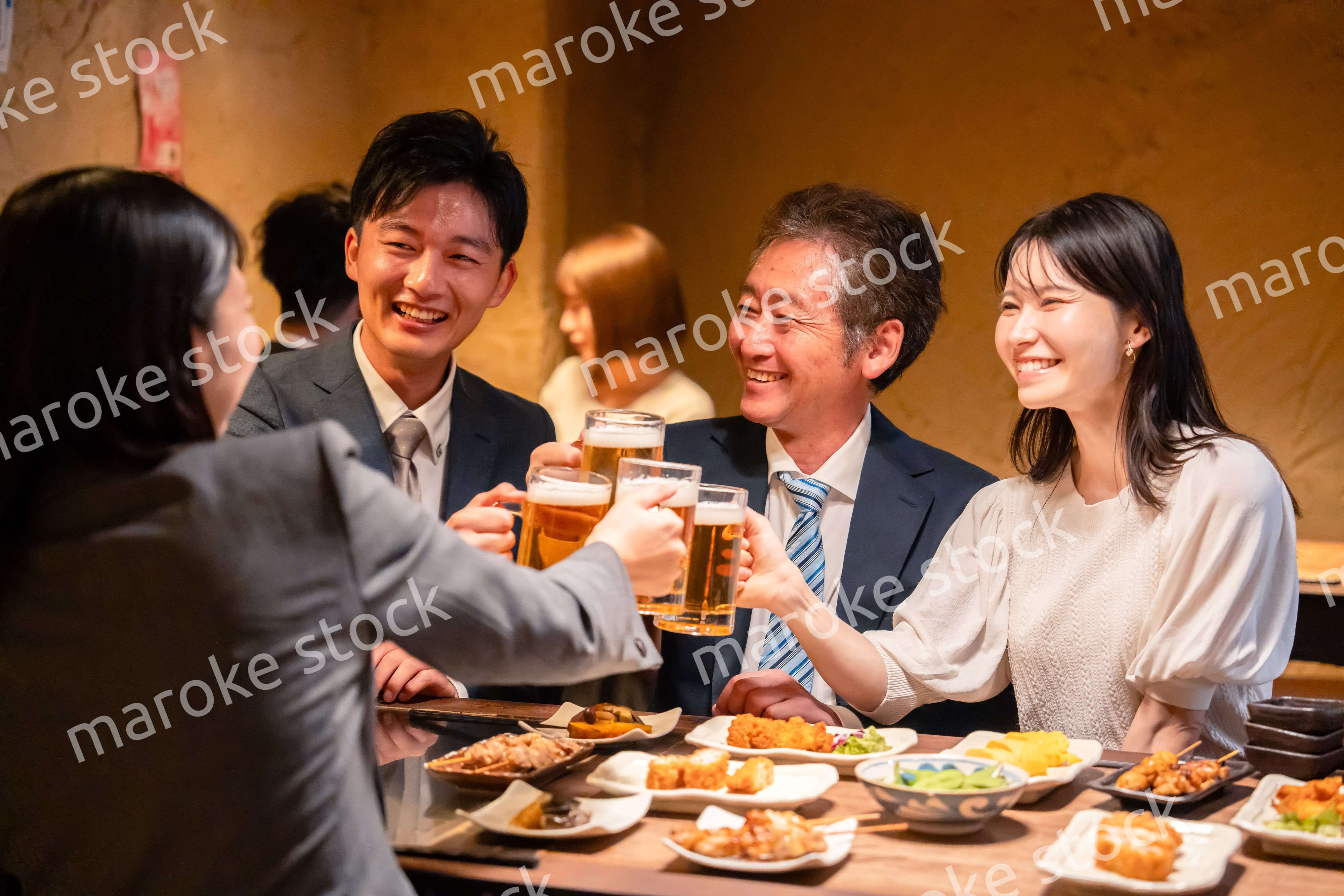 居酒屋で乾杯をする男女のビジネスパーソン