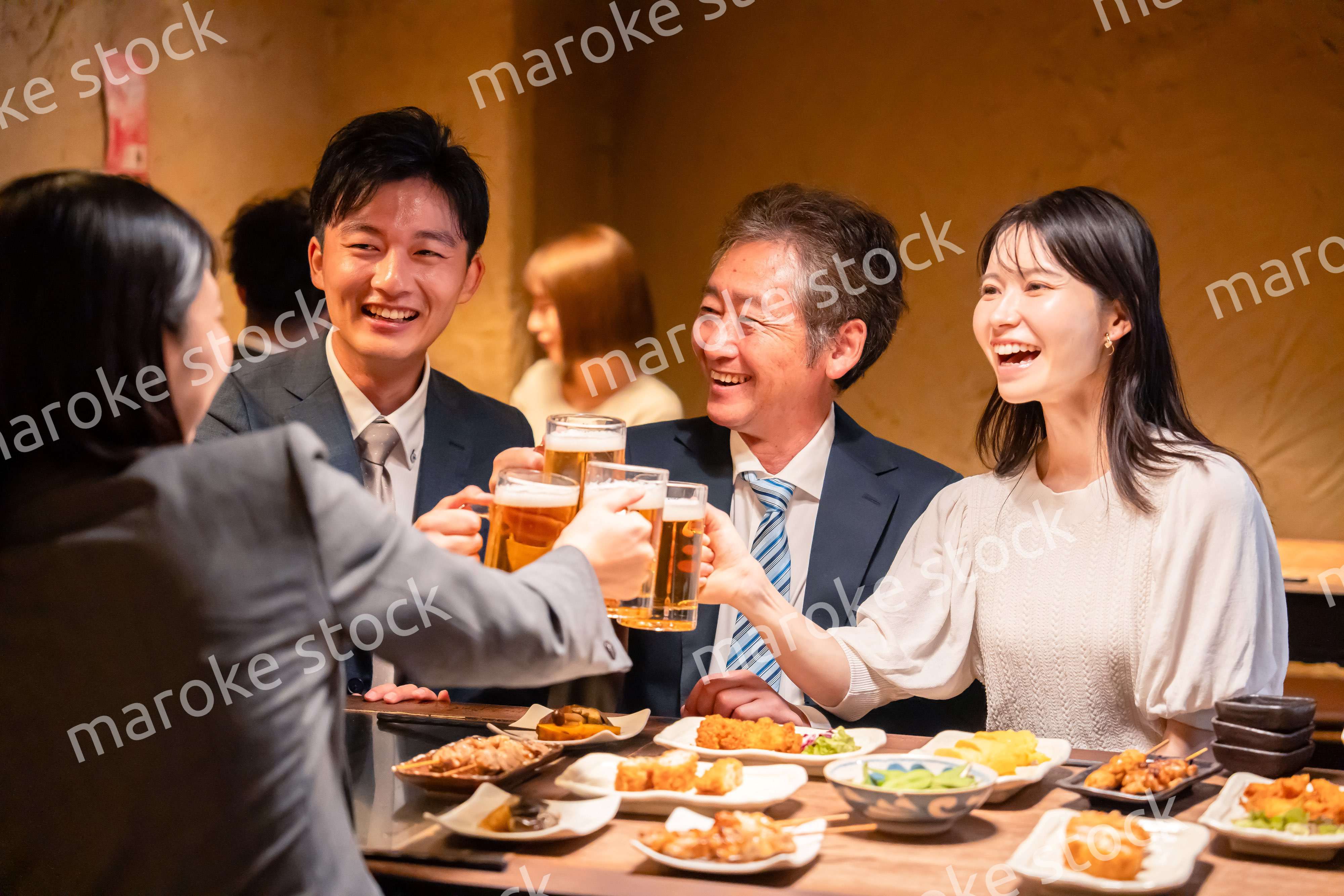 居酒屋で乾杯をする男女のビジネスパーソン