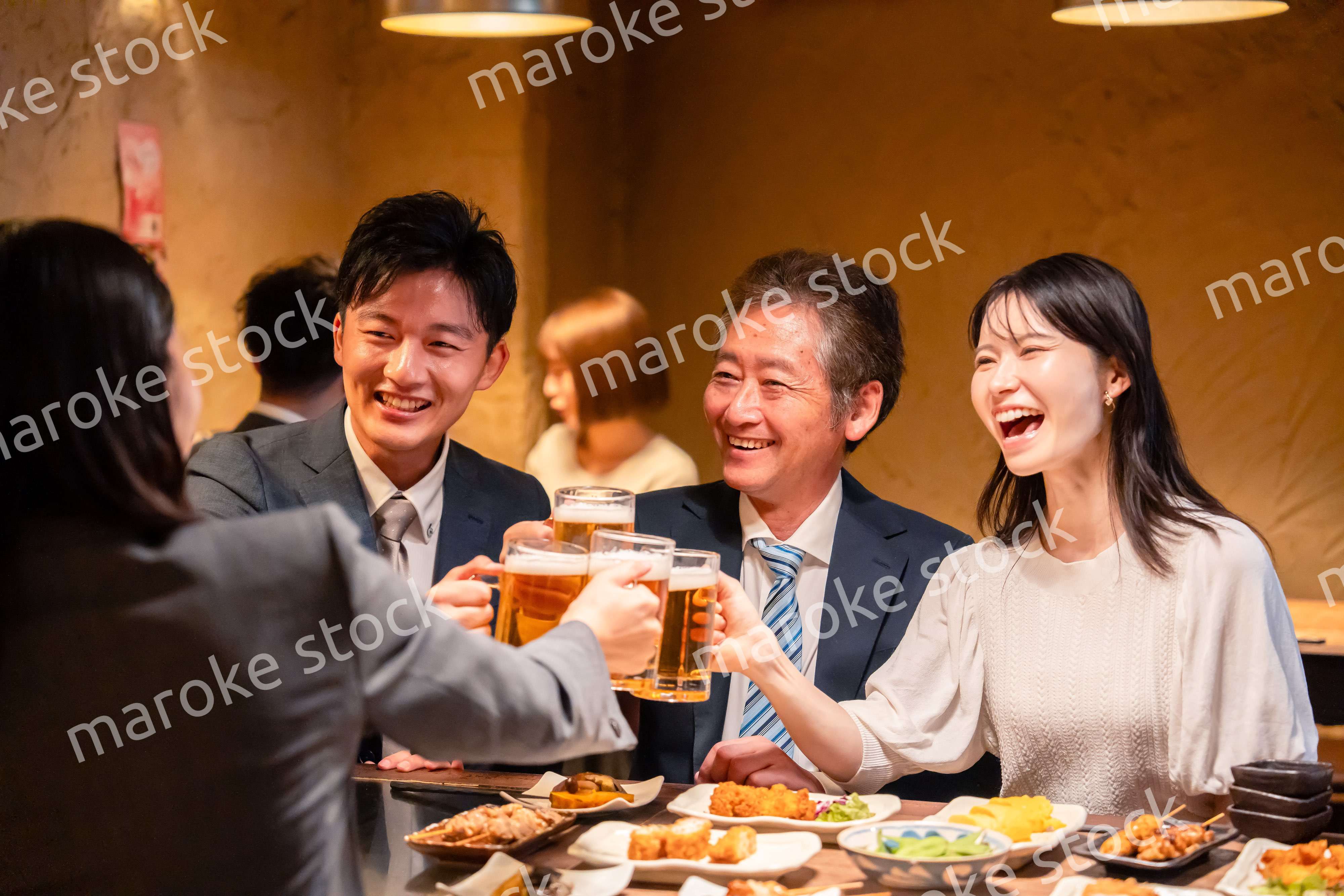 居酒屋で乾杯をする男女のビジネスパーソン