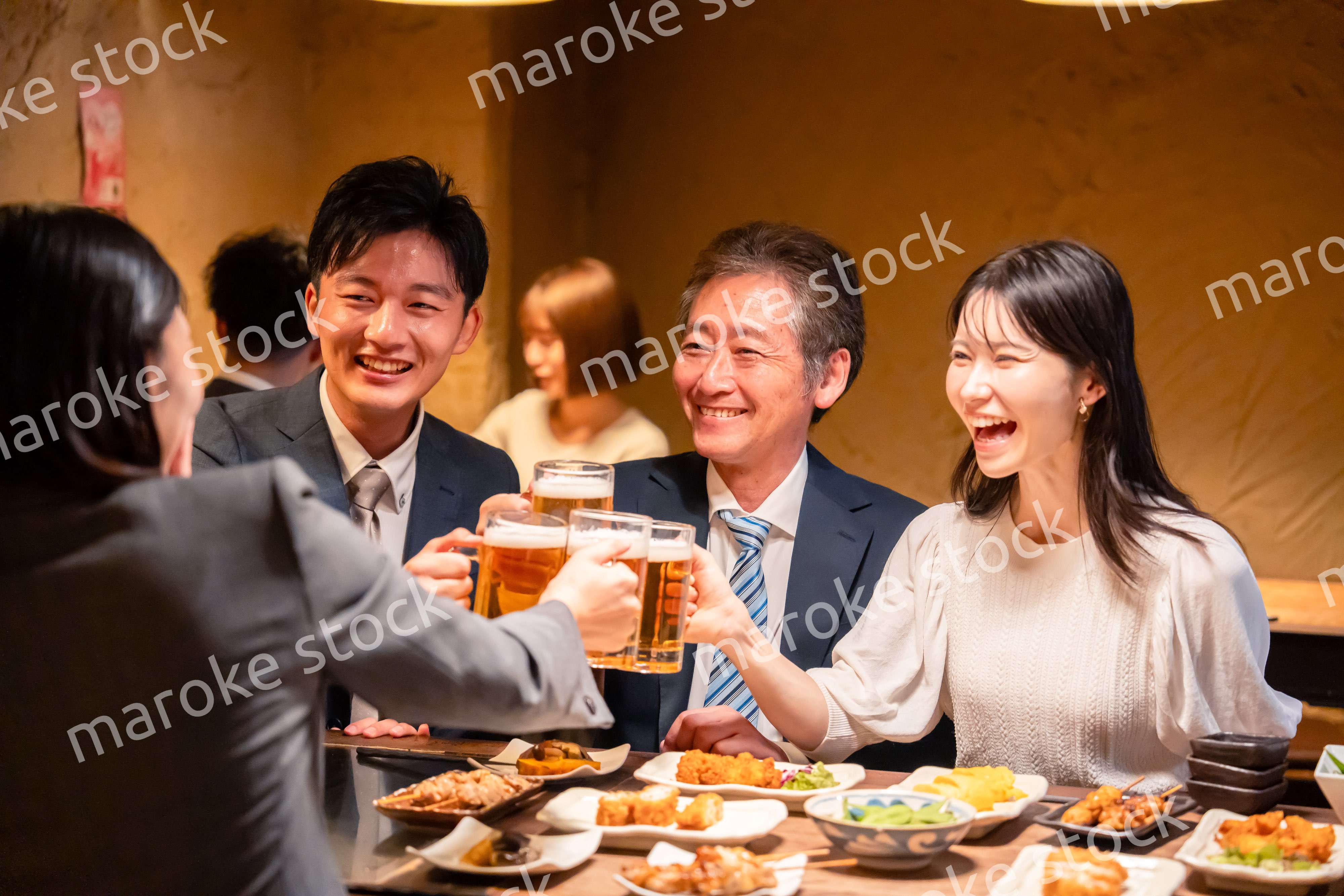 居酒屋で乾杯をする男女のビジネスパーソン