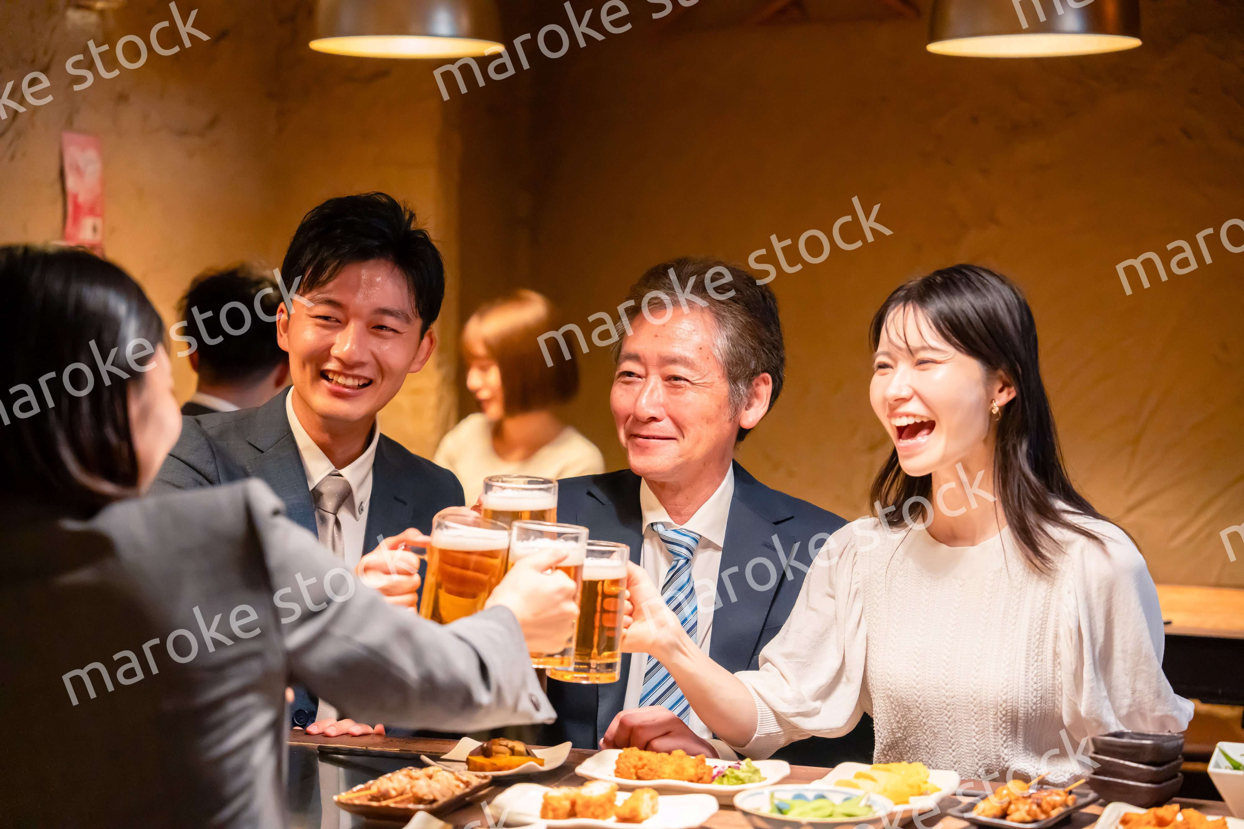 居酒屋で乾杯をする男女のビジネスパーソン