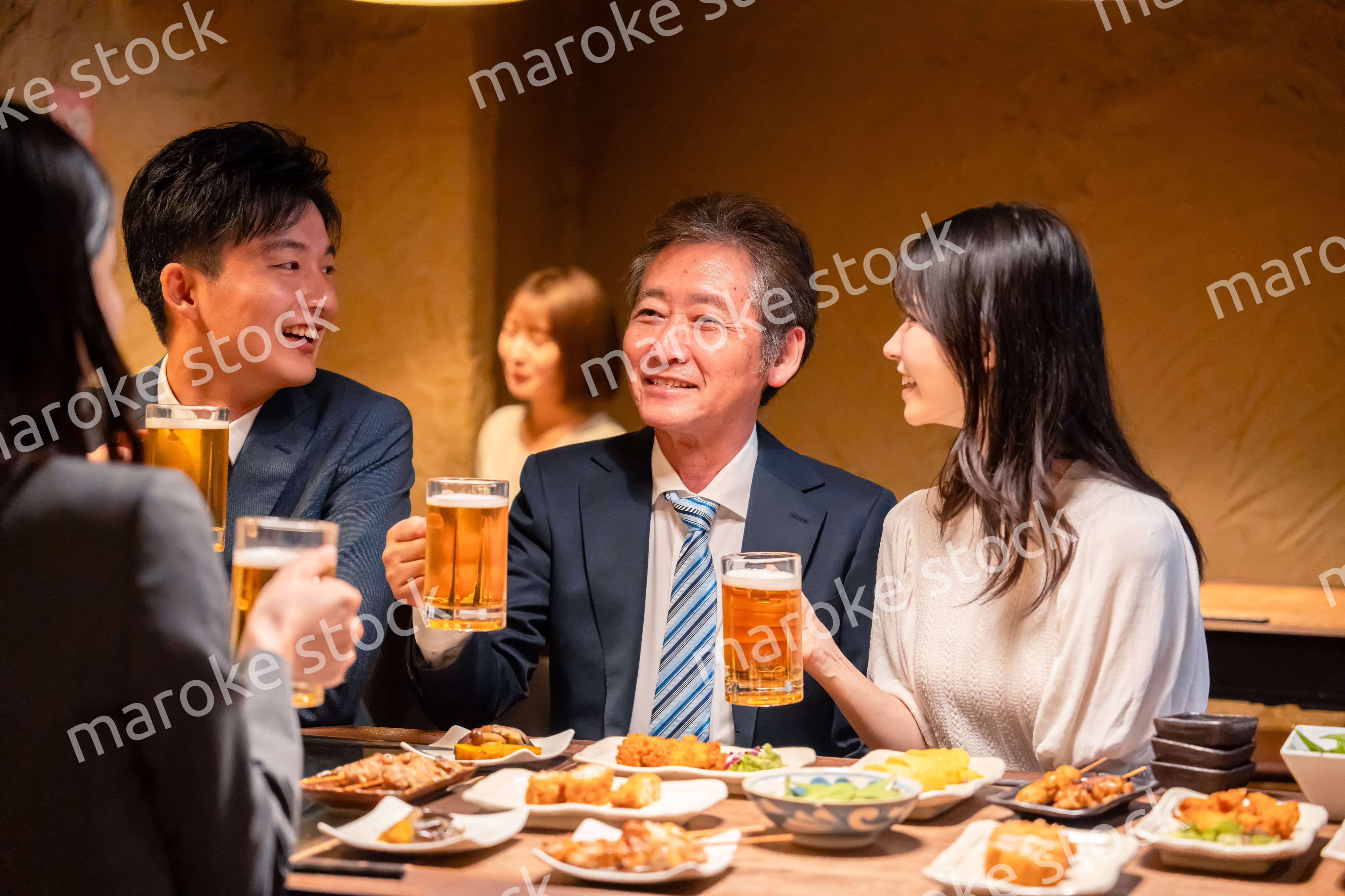 居酒屋で乾杯をする男女のビジネスパーソン