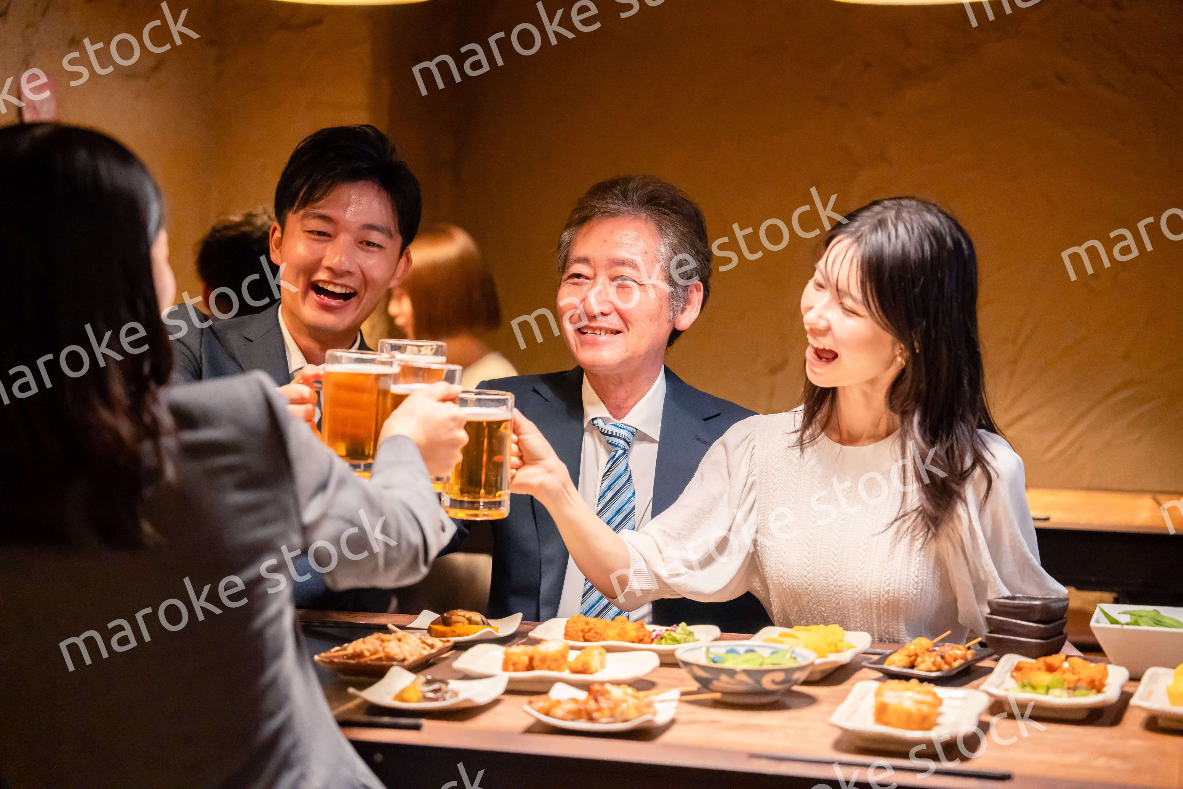 居酒屋で乾杯をする男女のビジネスパーソン