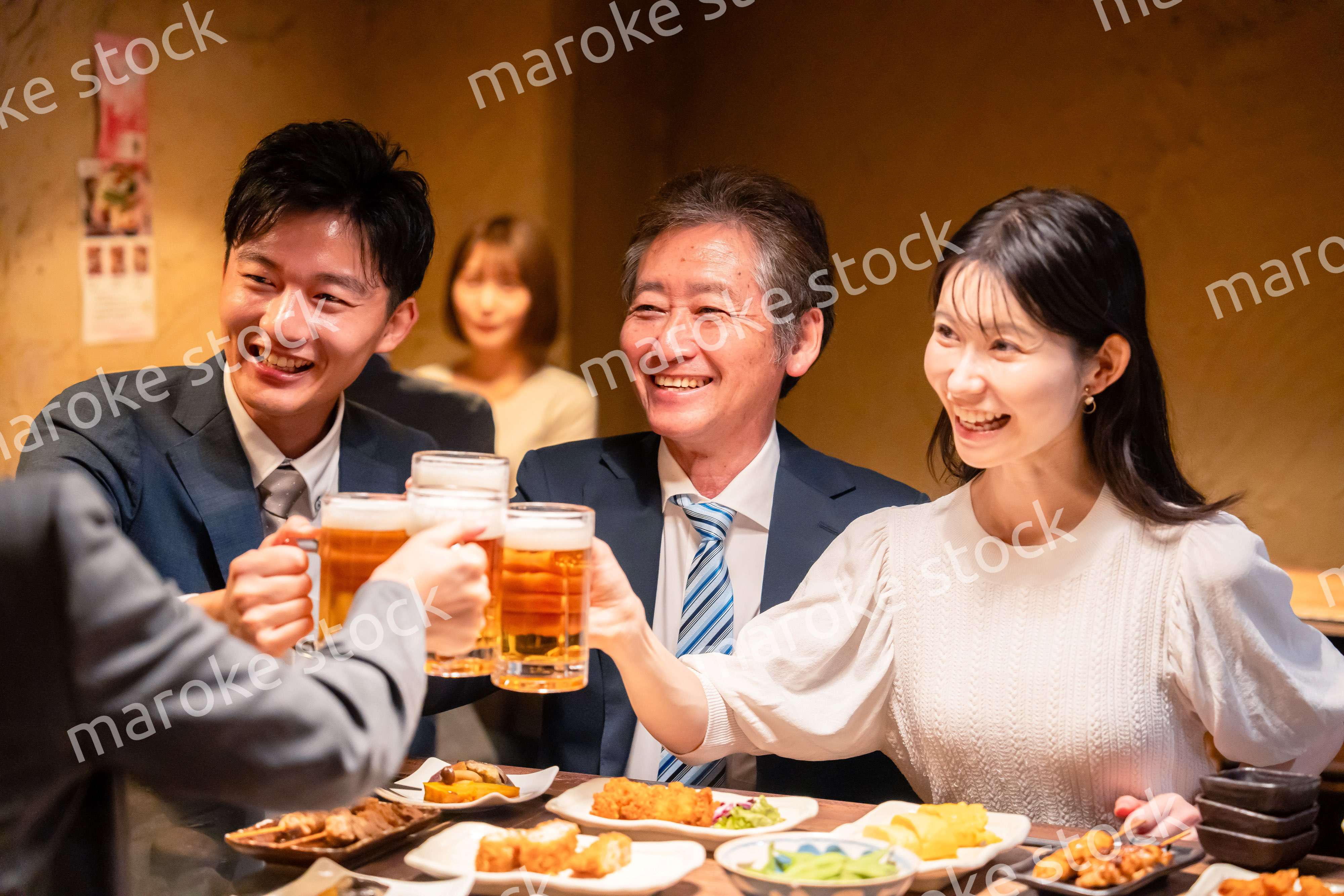 居酒屋で乾杯をする男女のビジネスパーソン