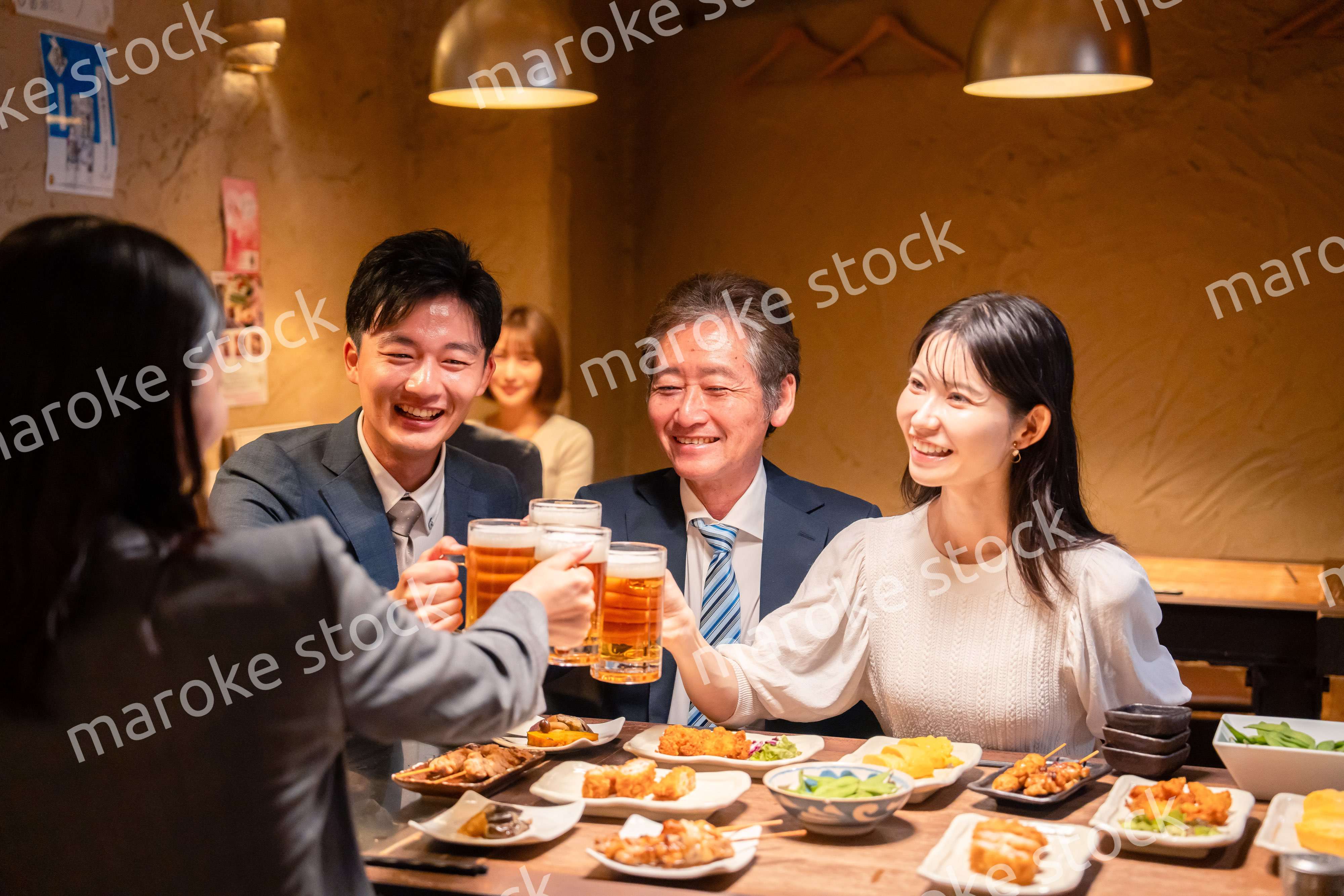 居酒屋で乾杯をする男女のビジネスパーソン