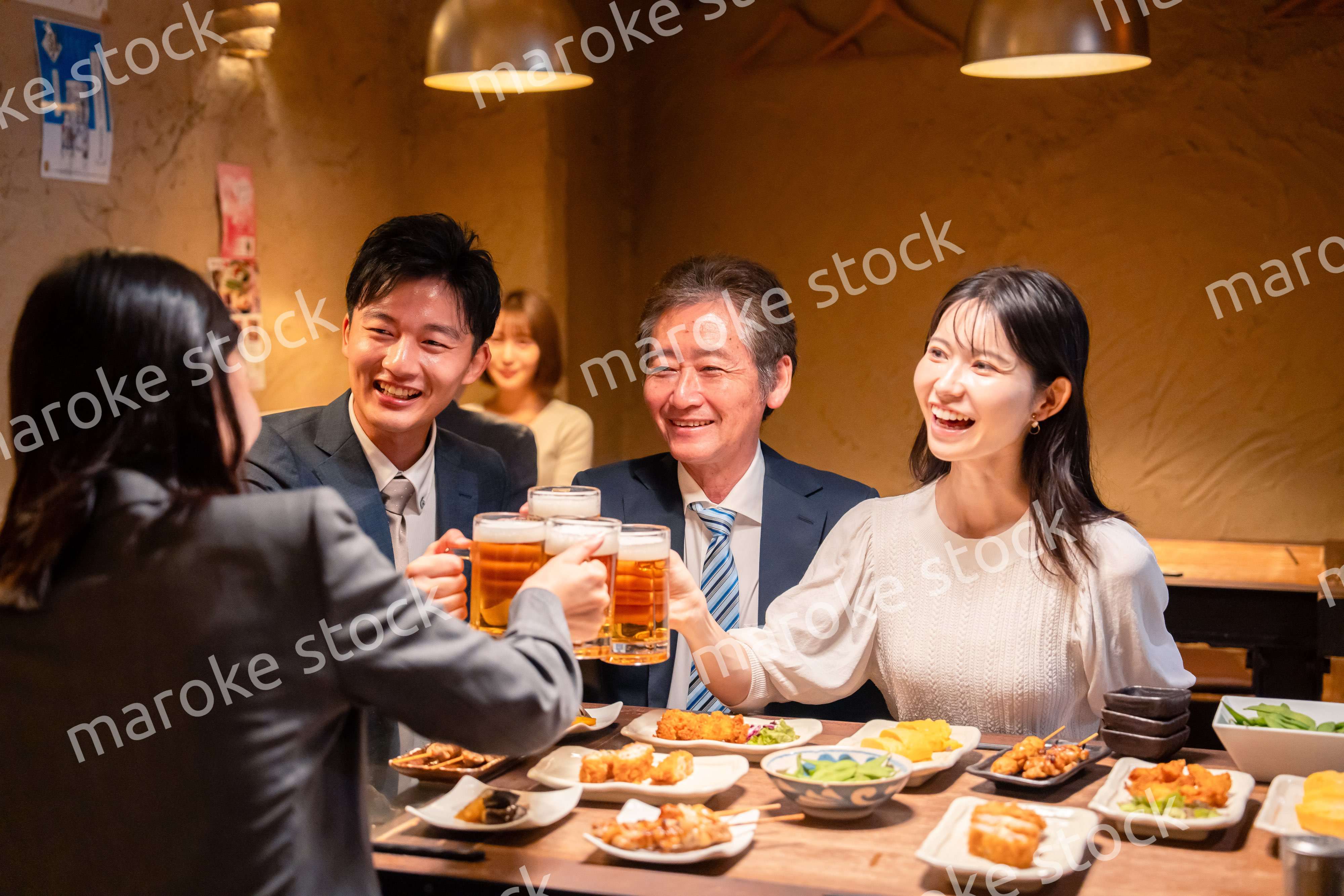 居酒屋で乾杯をする男女のビジネスパーソン