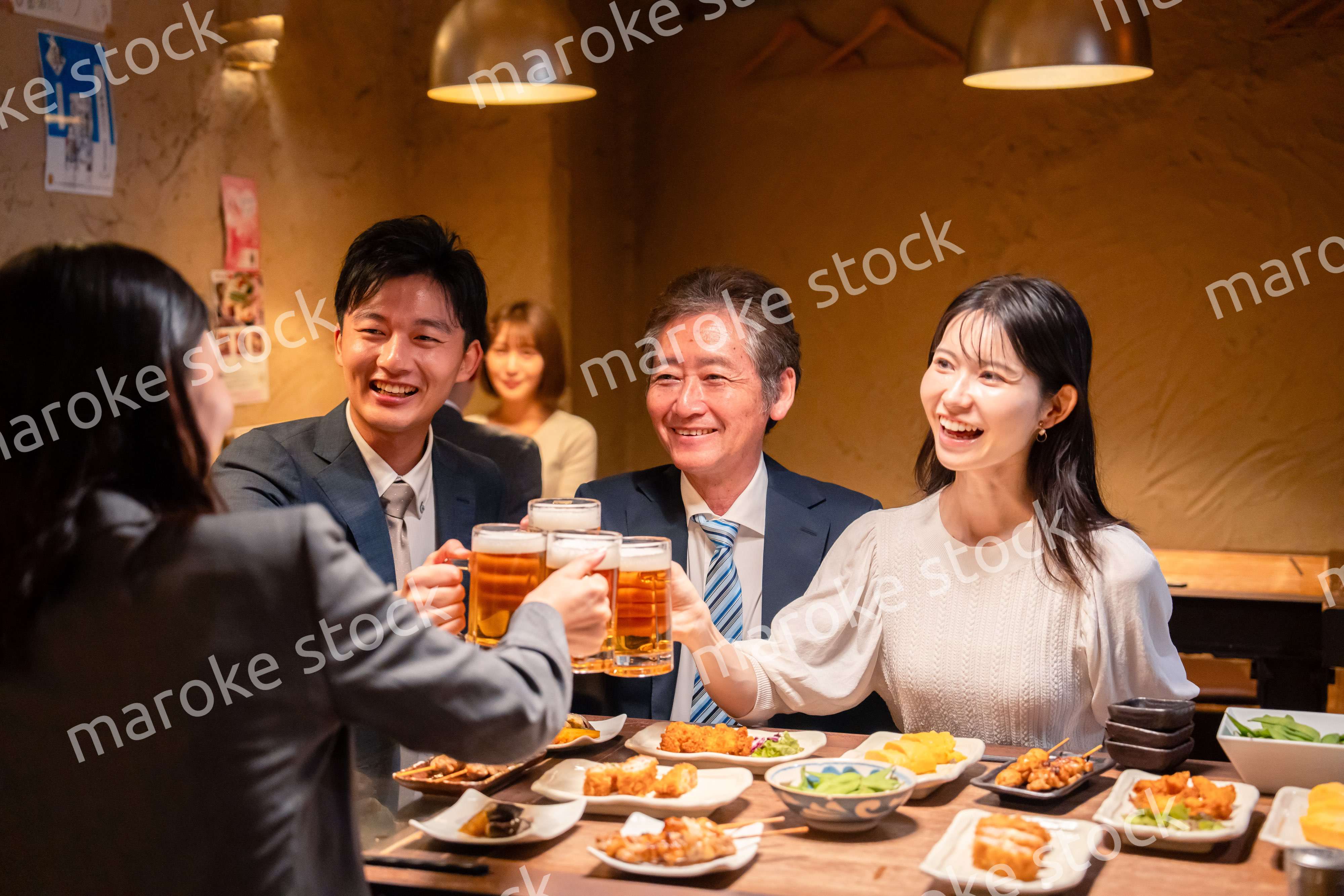 居酒屋で乾杯をする男女のビジネスパーソン