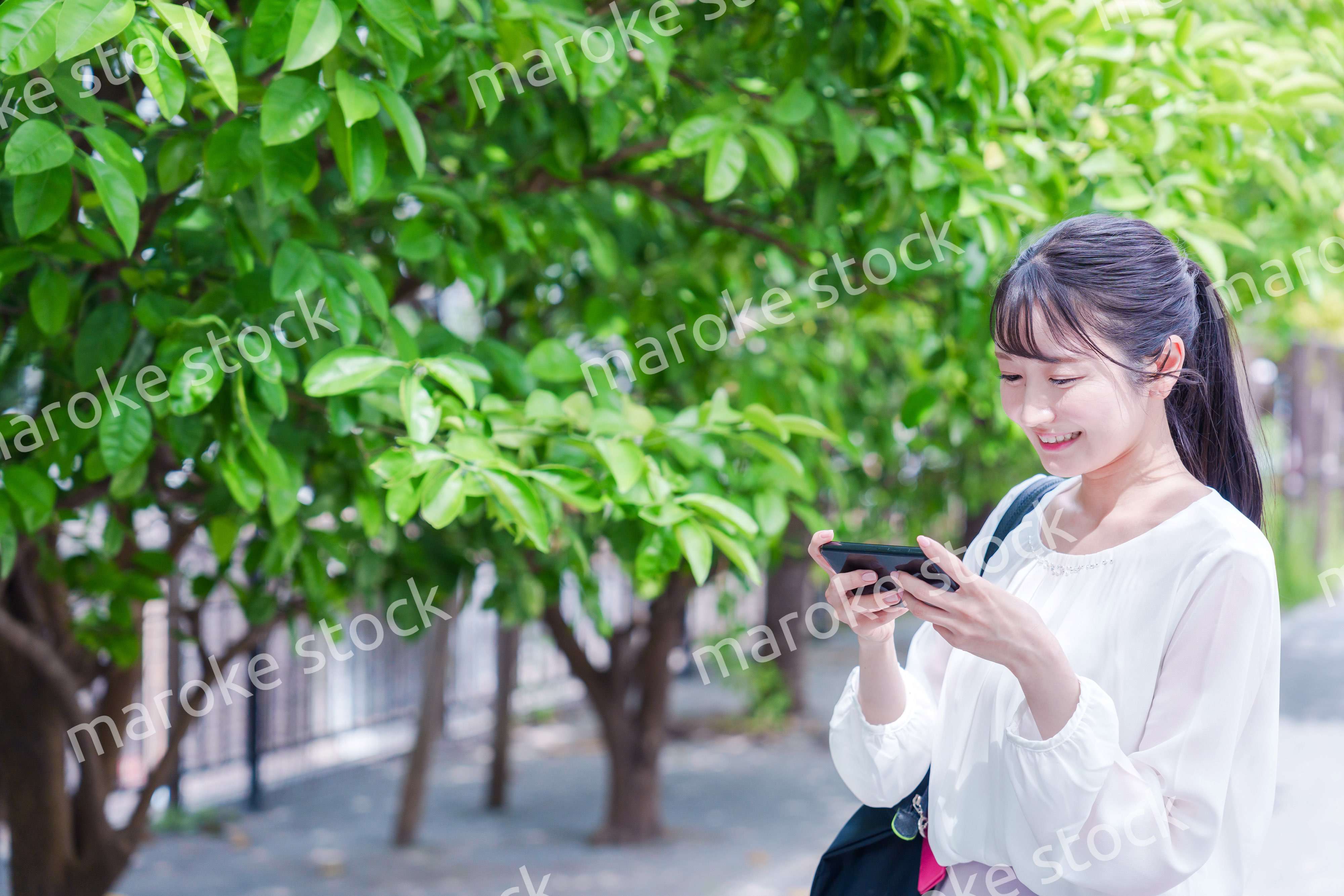 笑顔でスマホを見ながら歩く若い女性